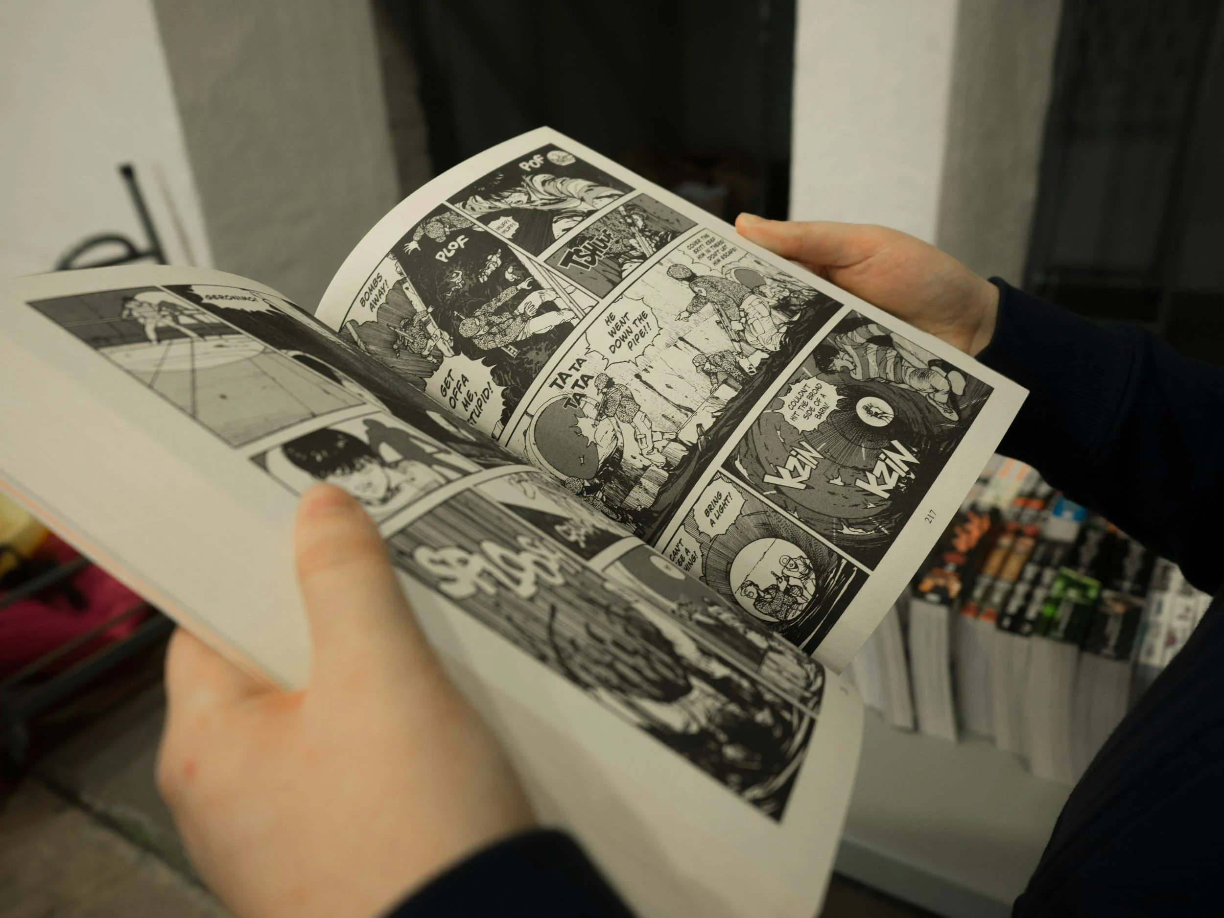 Person holding and reading an open black and white manga comic book at an event - Event Staffing Live