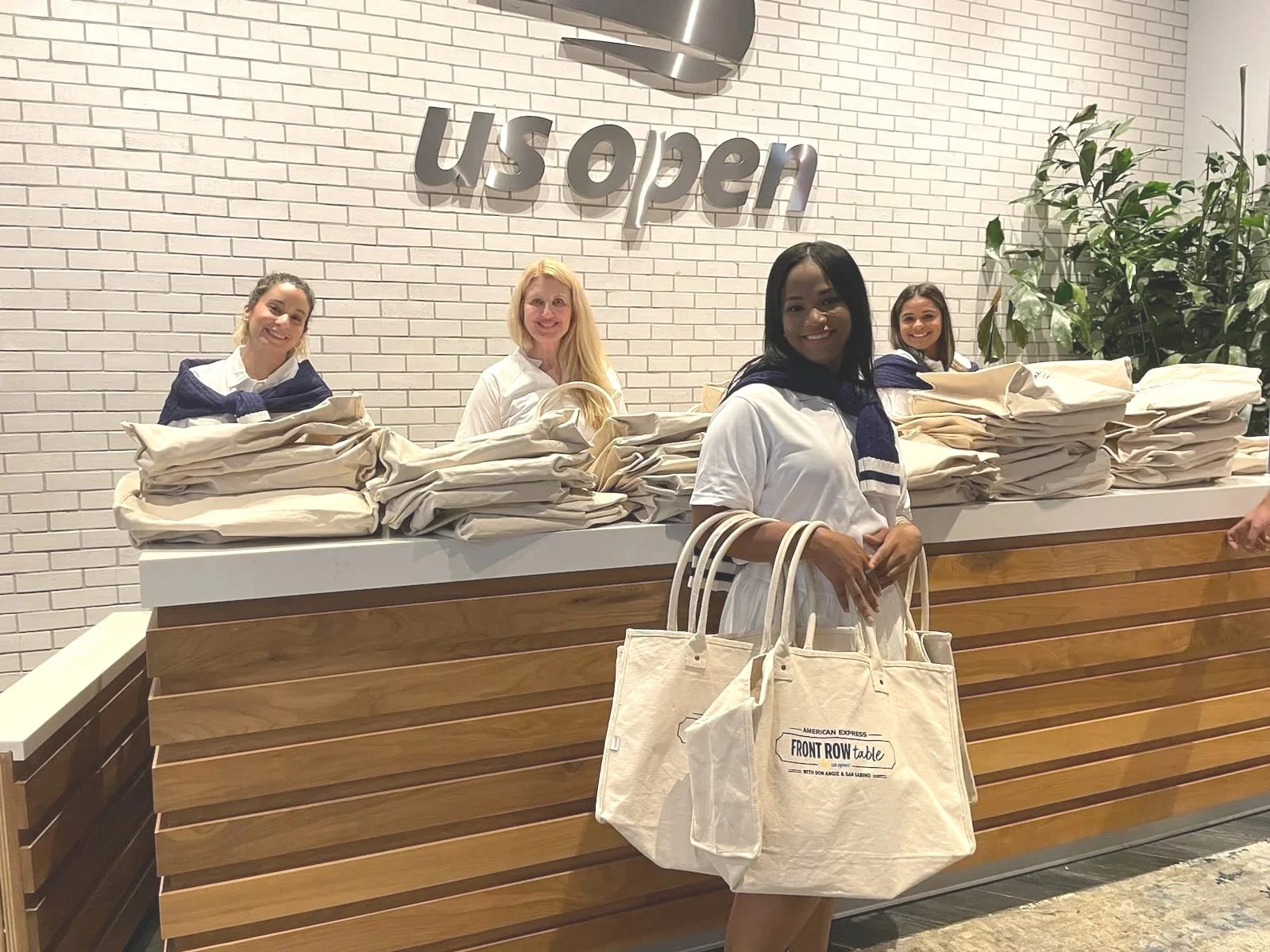 US Open event staff and brand ambassadors holding promotional tote bags at a registration counter - Event Staffing Live