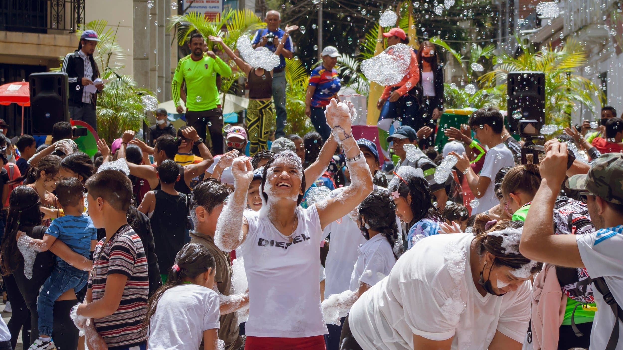 Enthusiastic crowd celebrating outdoors with soap suds and bubbles during a lively street foam party event