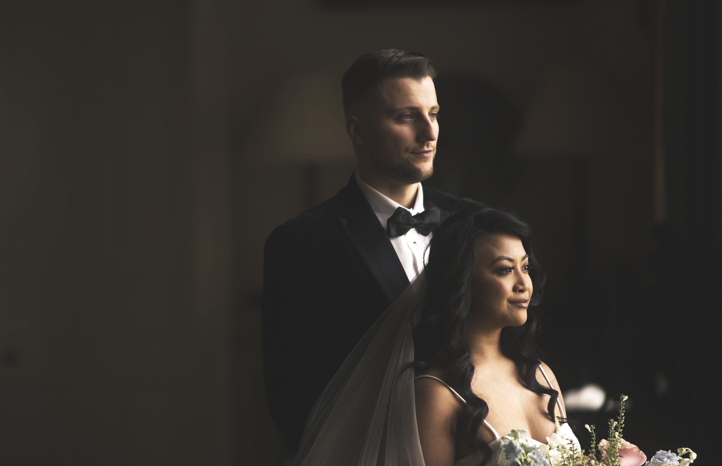 A frame from a London Wedding videographer of a married couple looking out of a window, groom is in black tie