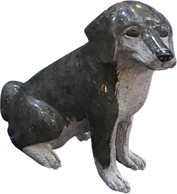 A stone sculpture of a dog sitting, with detailed features and a shiny surface.