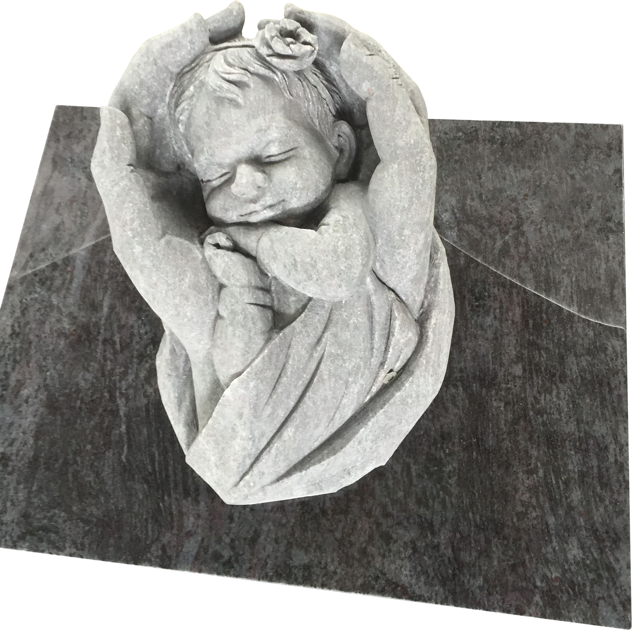 Gray stone carving of a sleeping baby with a flower in its hair, curled up with hands near its face, on a dark stone base.