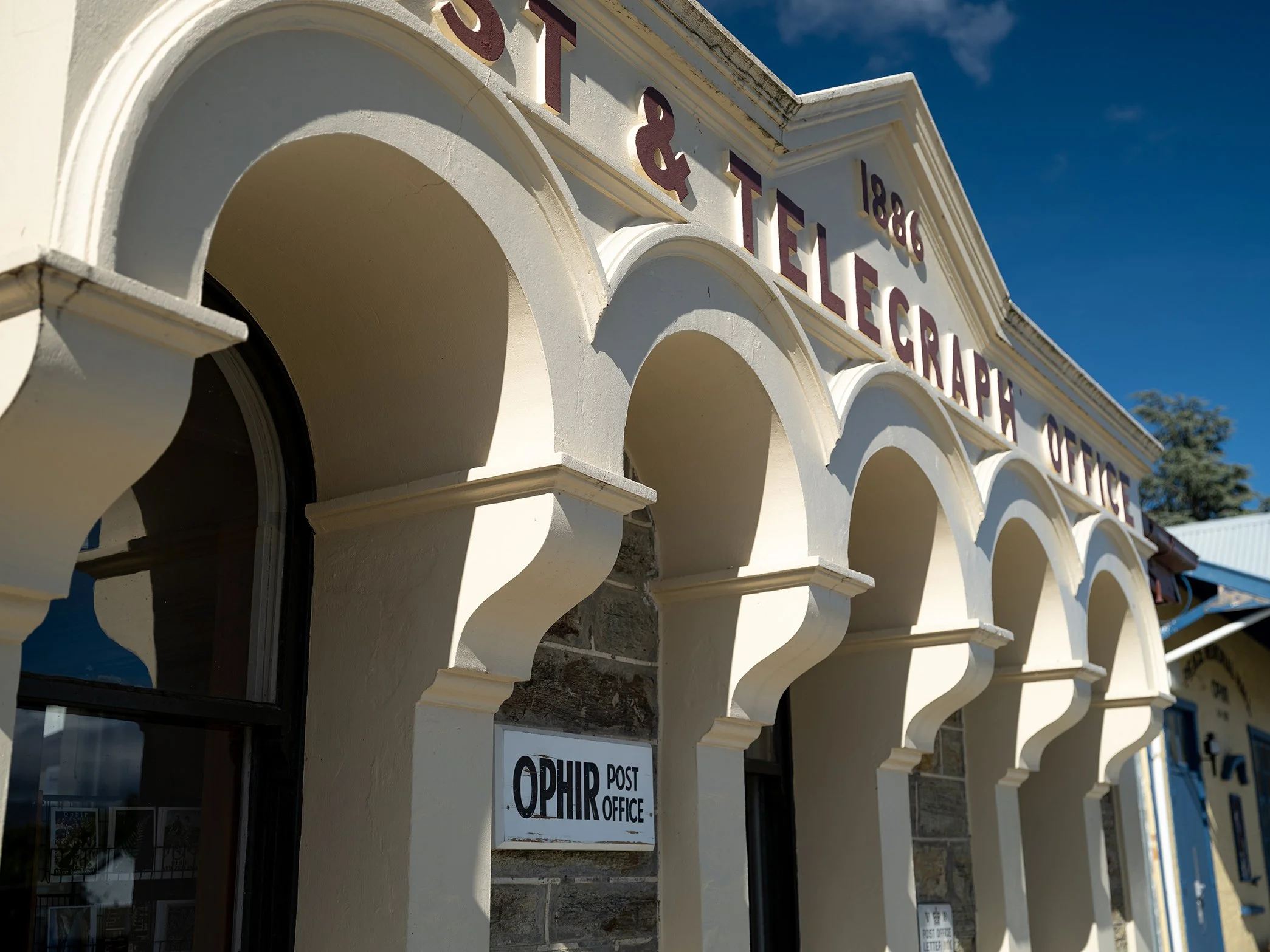 Exterior of a historic building with arches and a sign that reads '1886 Station & Telegraph Office' and a smaller sign that says 'Ophir Post Office'.
