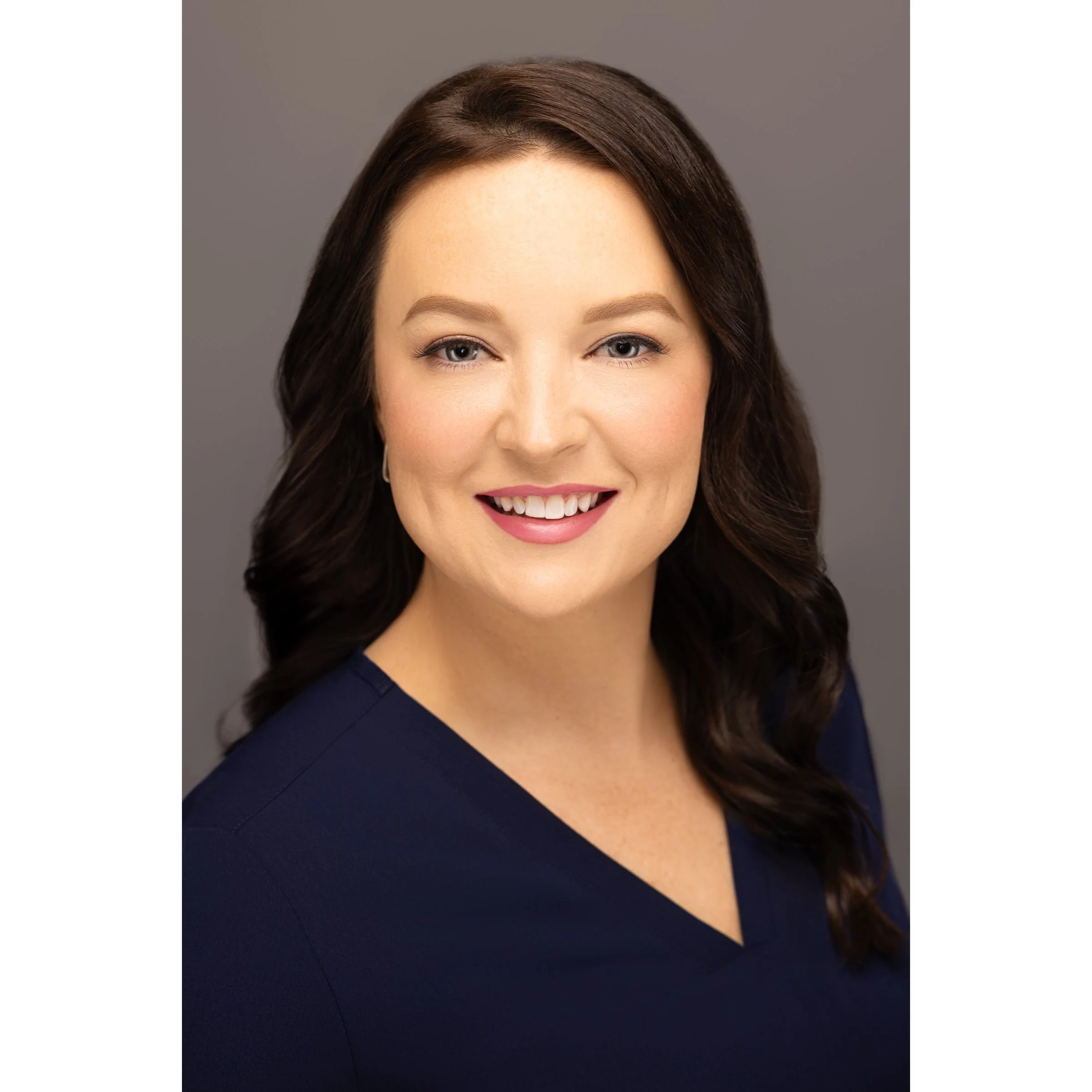 Woman smiling in a portrait with dark hair and a blue top