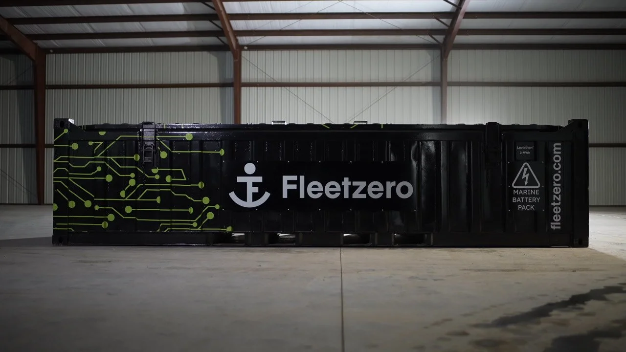 Black marine battery container with Fleetzero branding and circuit design, located inside a warehouse.