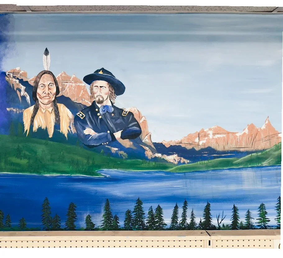 Sitting Bull and General Custer on left side of image in front of mountain landscape featuring large lake in foreground
