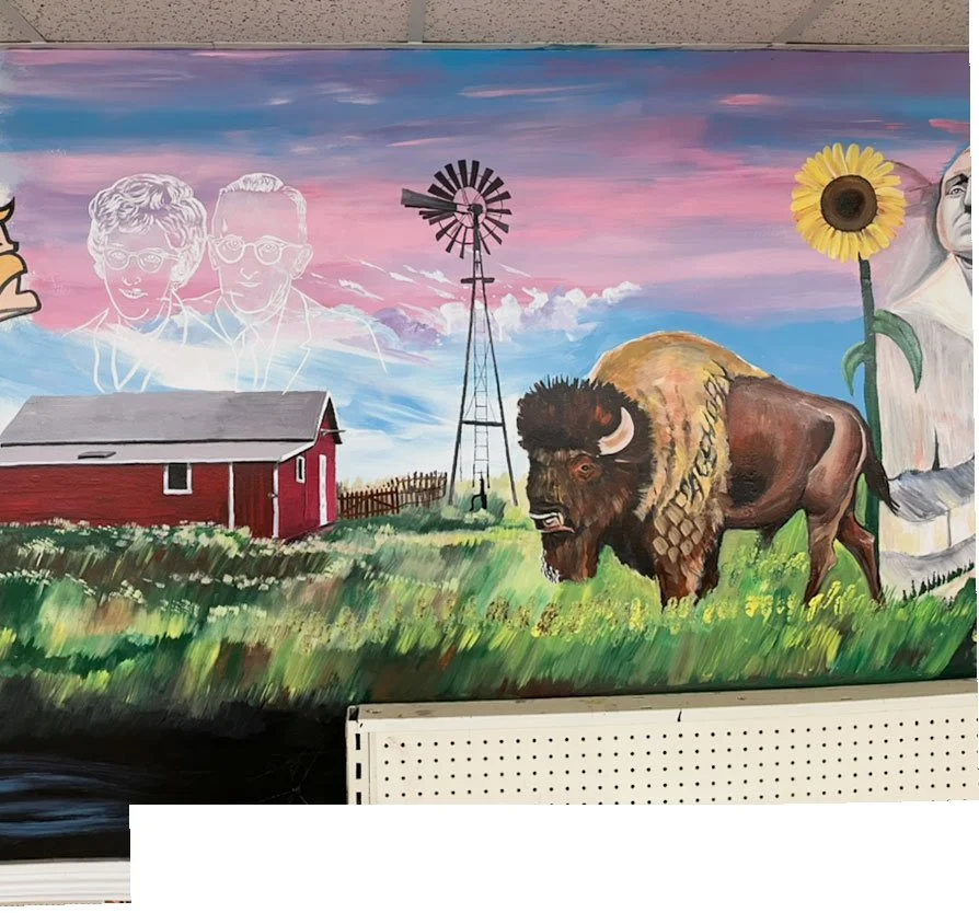small red barn under silhouette of two people on left side, windmill in center, bison to right next to sunflower and part of Mount Rushmore on right