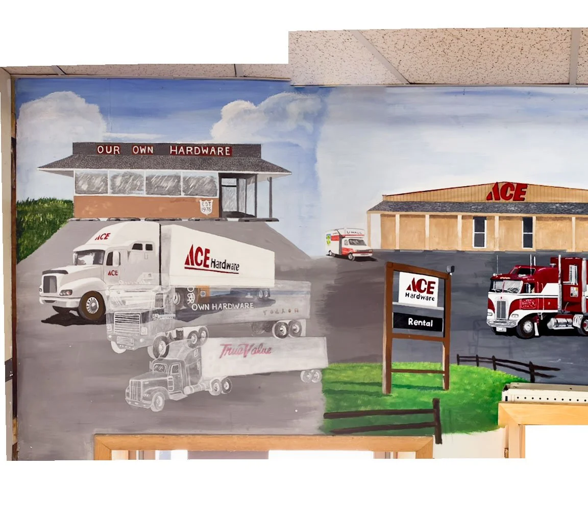 store outline in back left with Our Own Hardware sign on roof, Ace Hardware semi truck below it with ghostly outline of Our Own Hardware and True Value semis in front of it. store outline on right with Ace sign on roof, U-Haul parked to left of build