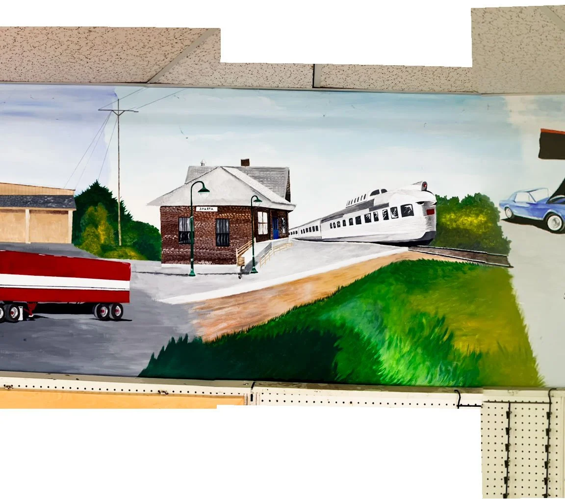 part of store outline and BJ and the Bear semi truck on left side, Sparta train station in center with California Zephyr train going past, small grassy area below