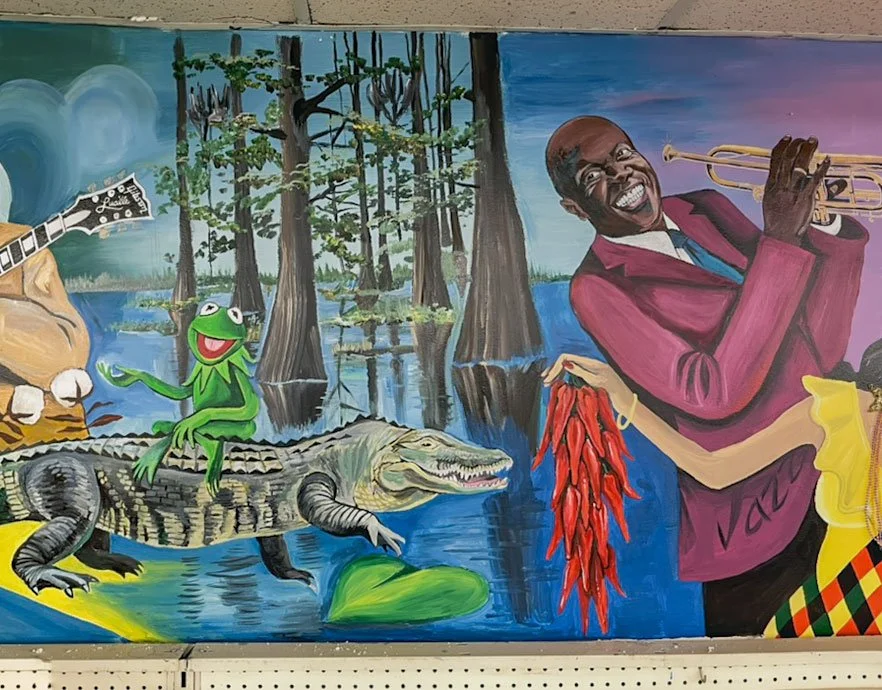 Bayou with alligator on left side, Kermit the Frog riding alligator, jazz musician Louis Armstrong on right, woman's arm holding chilis under him