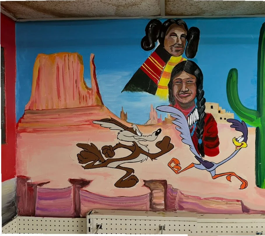 Butte in back left, Road Runner and Willie Coyote underneath, two Native Americans behind and above them, cactus on right edge