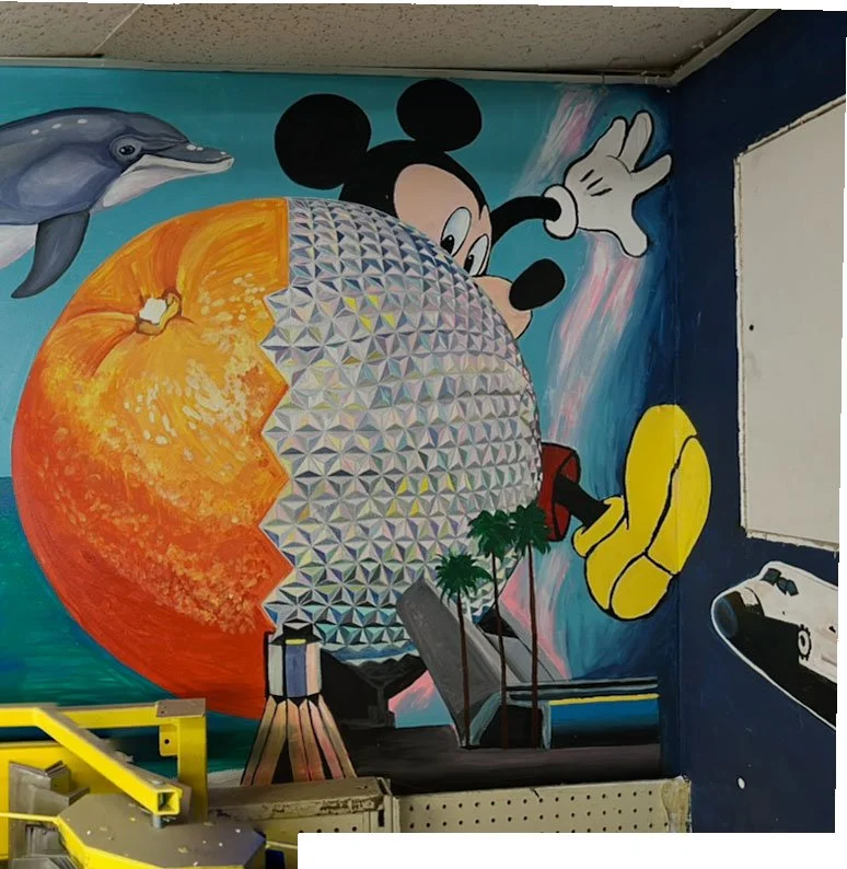 head of leaping dolphin on left side, half orange half Epcot globe in center, Mickey Mouse peaking out from behind Epcot globe, space shuttle in lower right corner