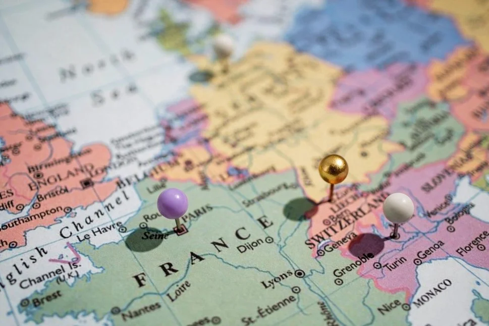 Close-up of a map of Europe with three colored pins marking Paris in France, Geneva in Switzerland, and Nice in France.