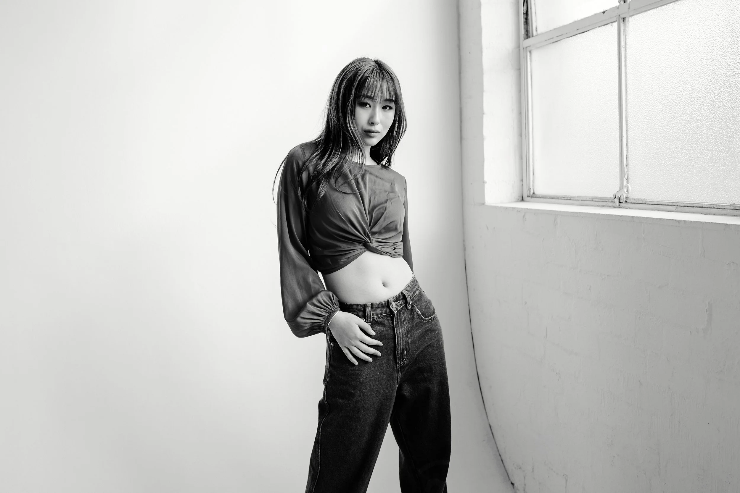 Strong, beautiful, defiant image of Andrea Djou in black and white with a white studio background.