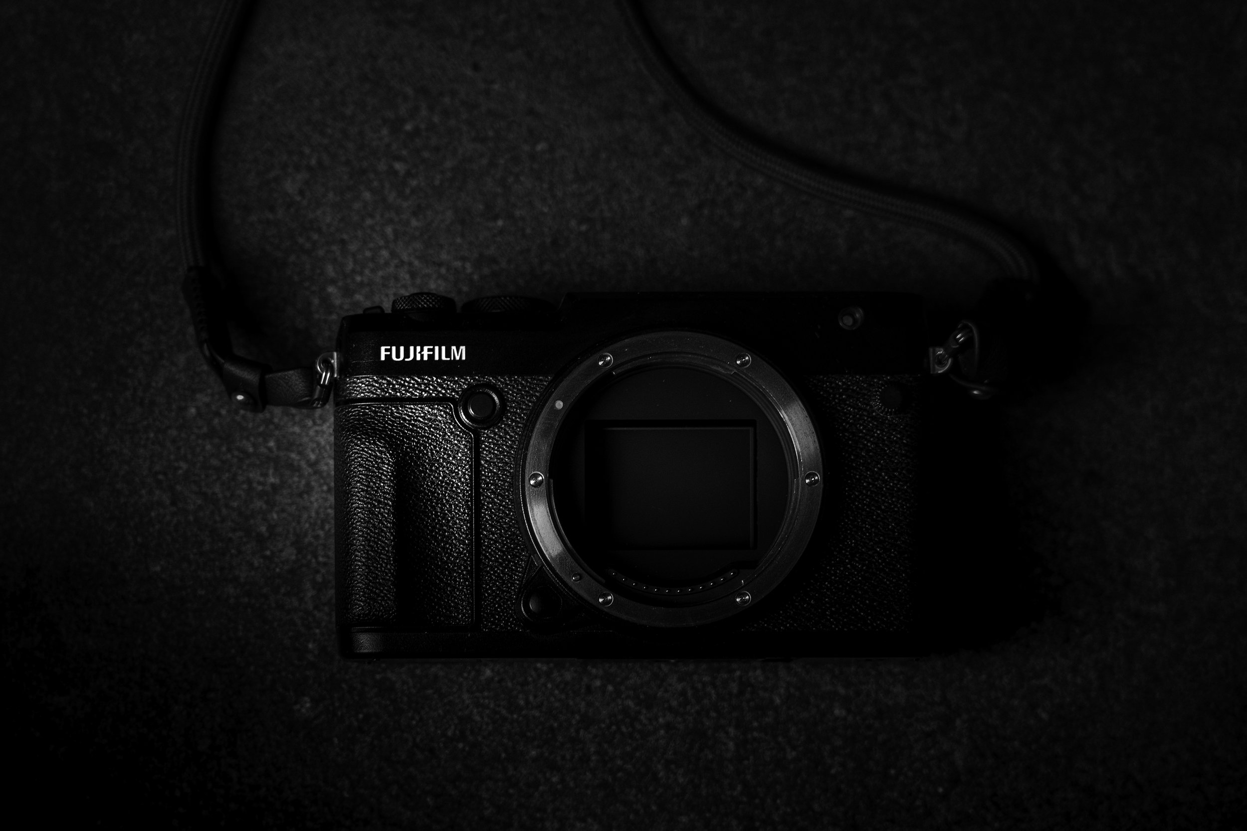 Black and white image of a Fujifilm GFX 50R, shot top down on a black background.