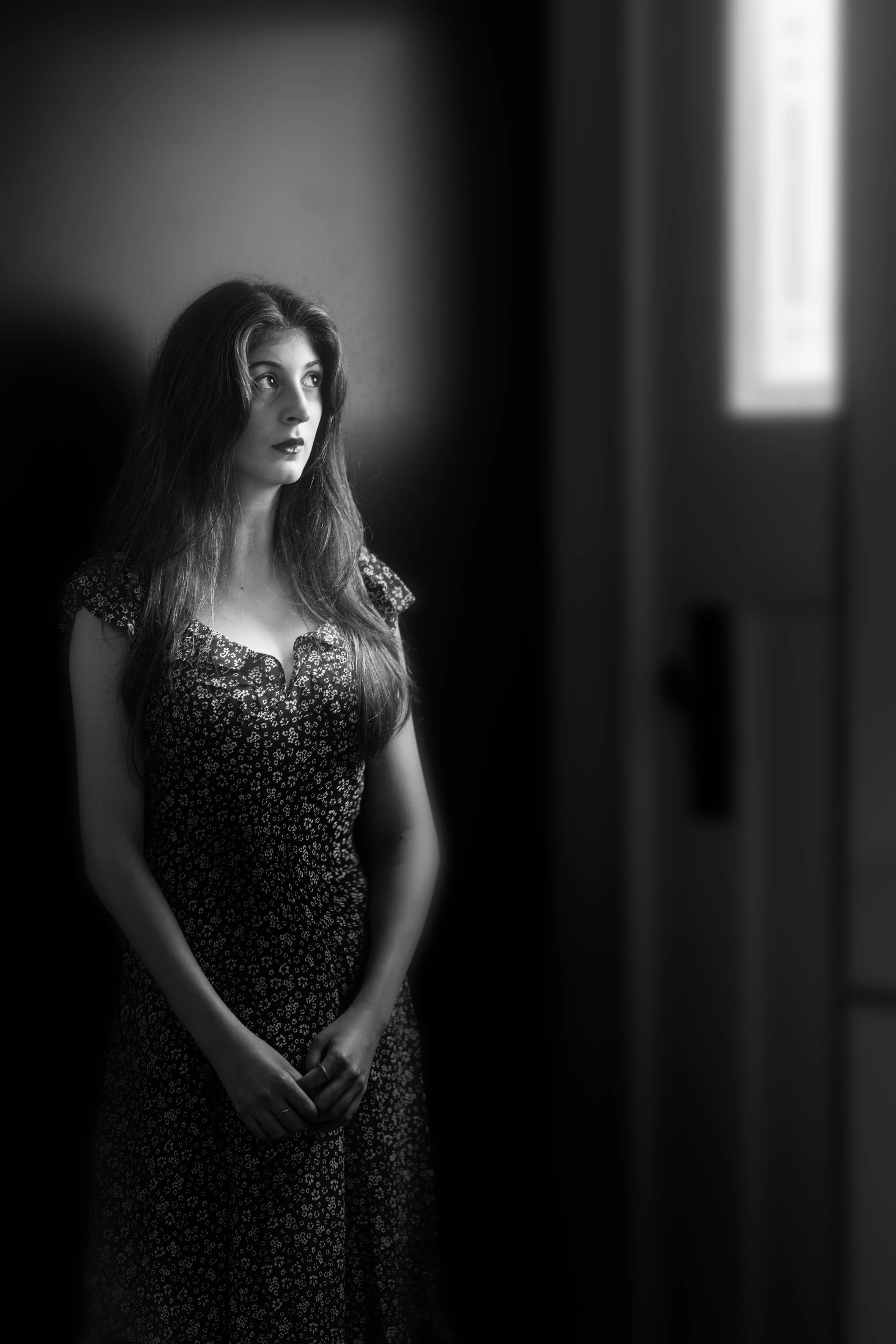 Full-length photo of Angel Lamesa in Melbourne, wearing a dark dress with bare arms and brightly-lit face.