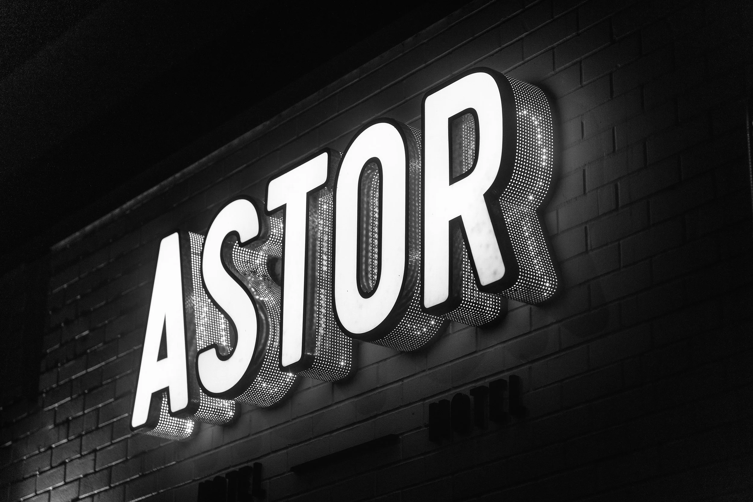 The Astor Hotel Sign, in Albury, illuminated at night, in black and white.
