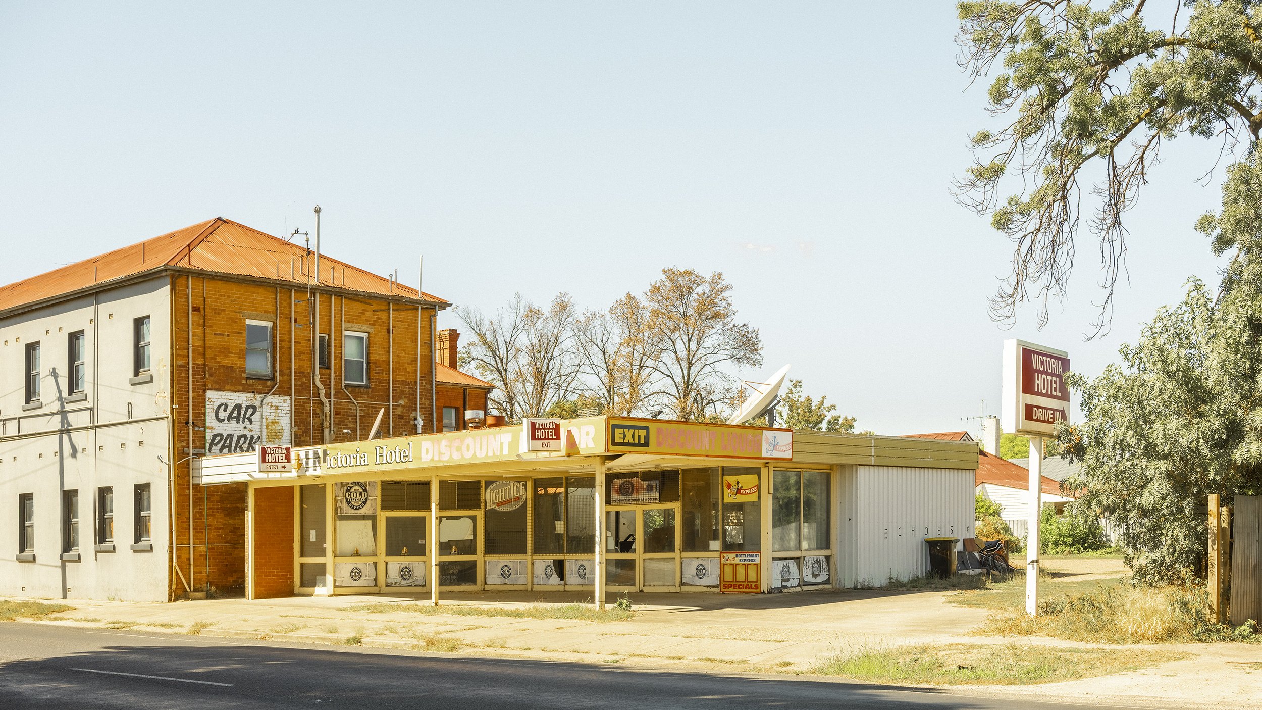 The historic Victoria Hotel in Benalla, side view, unrestored, bottle shop at the back with broken windows, hot sunny day.