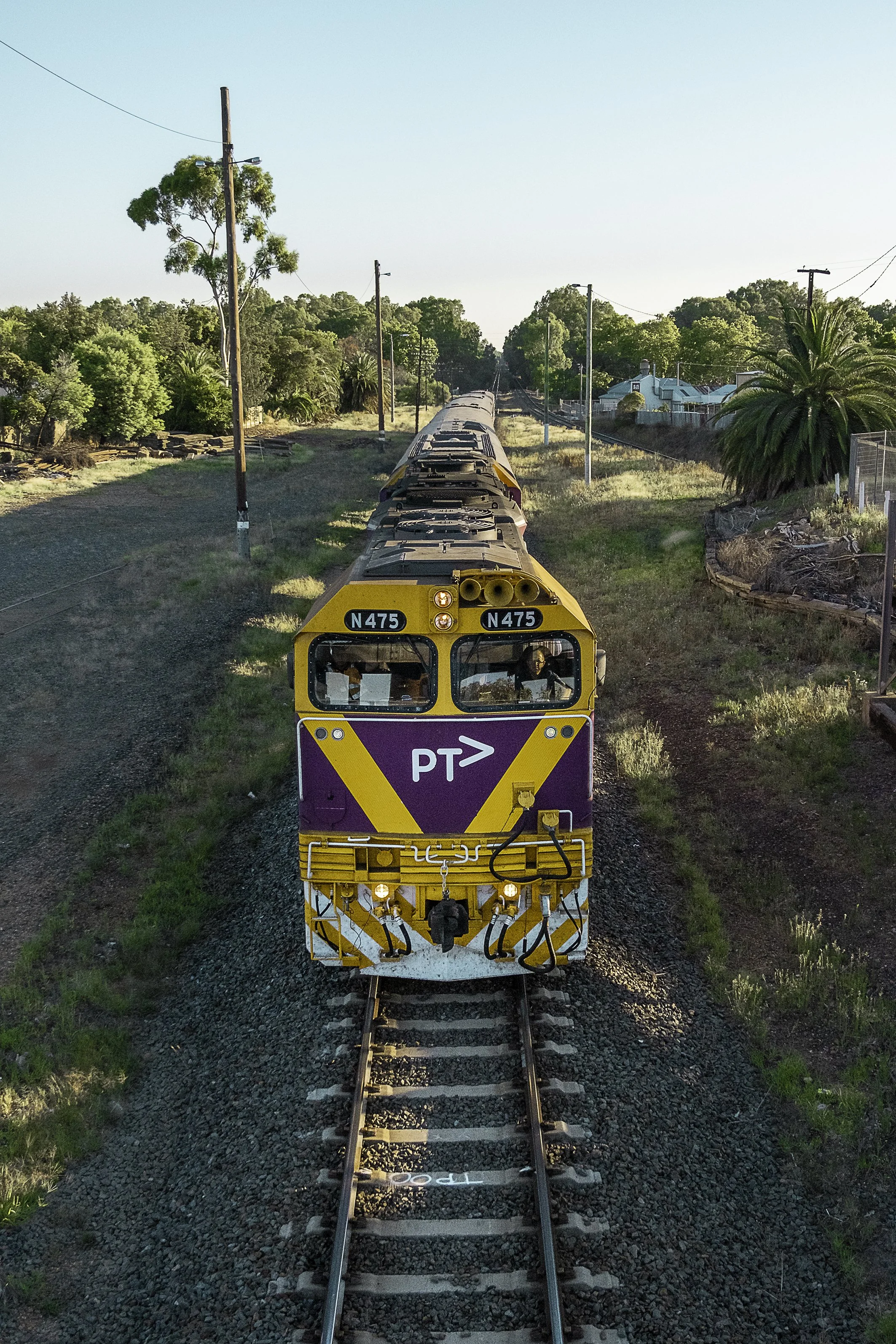Train pulls into Wangaratta Railway Station in bright summer sun.