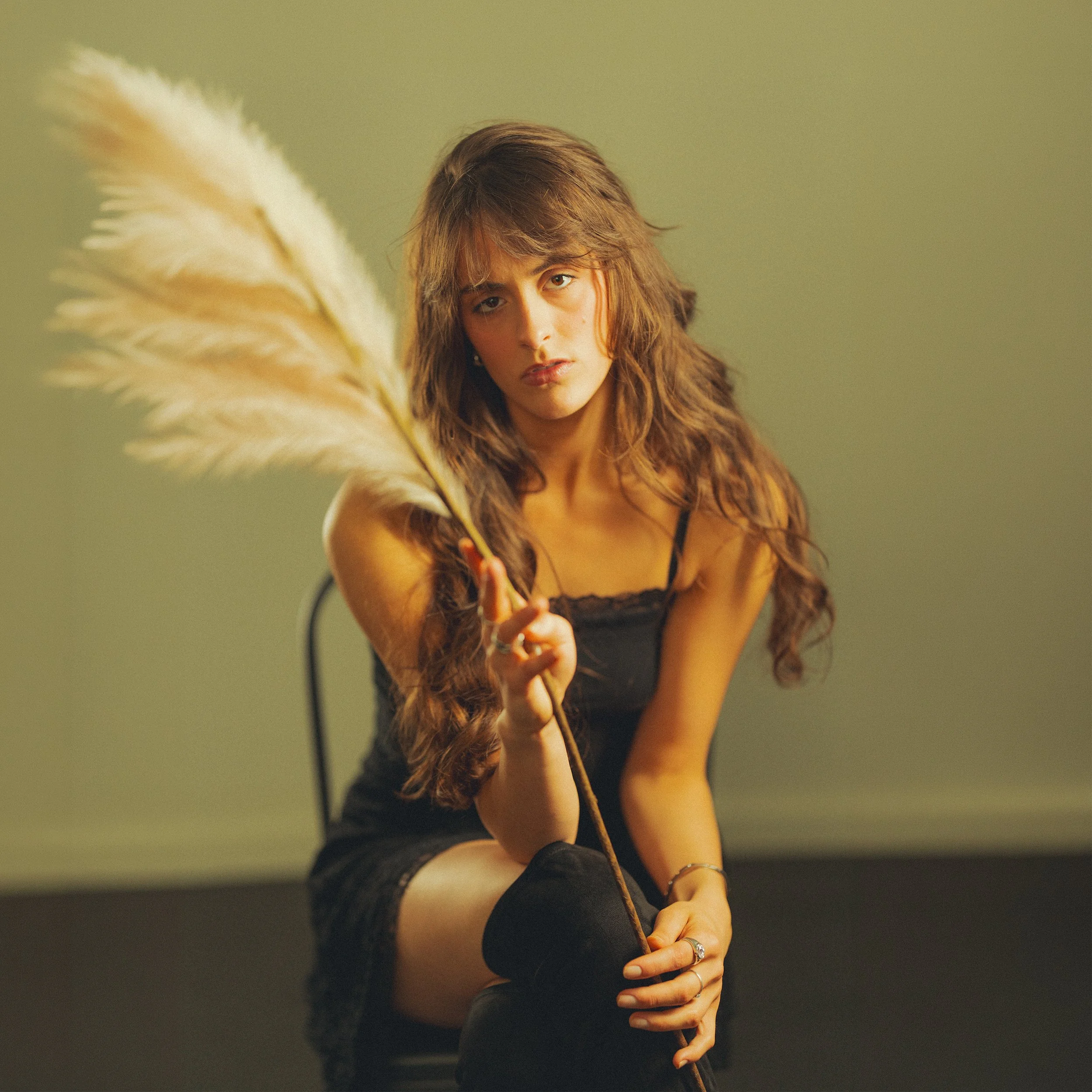 Singer Eadiella sitting in a chair, holding a feather, looking emotional.