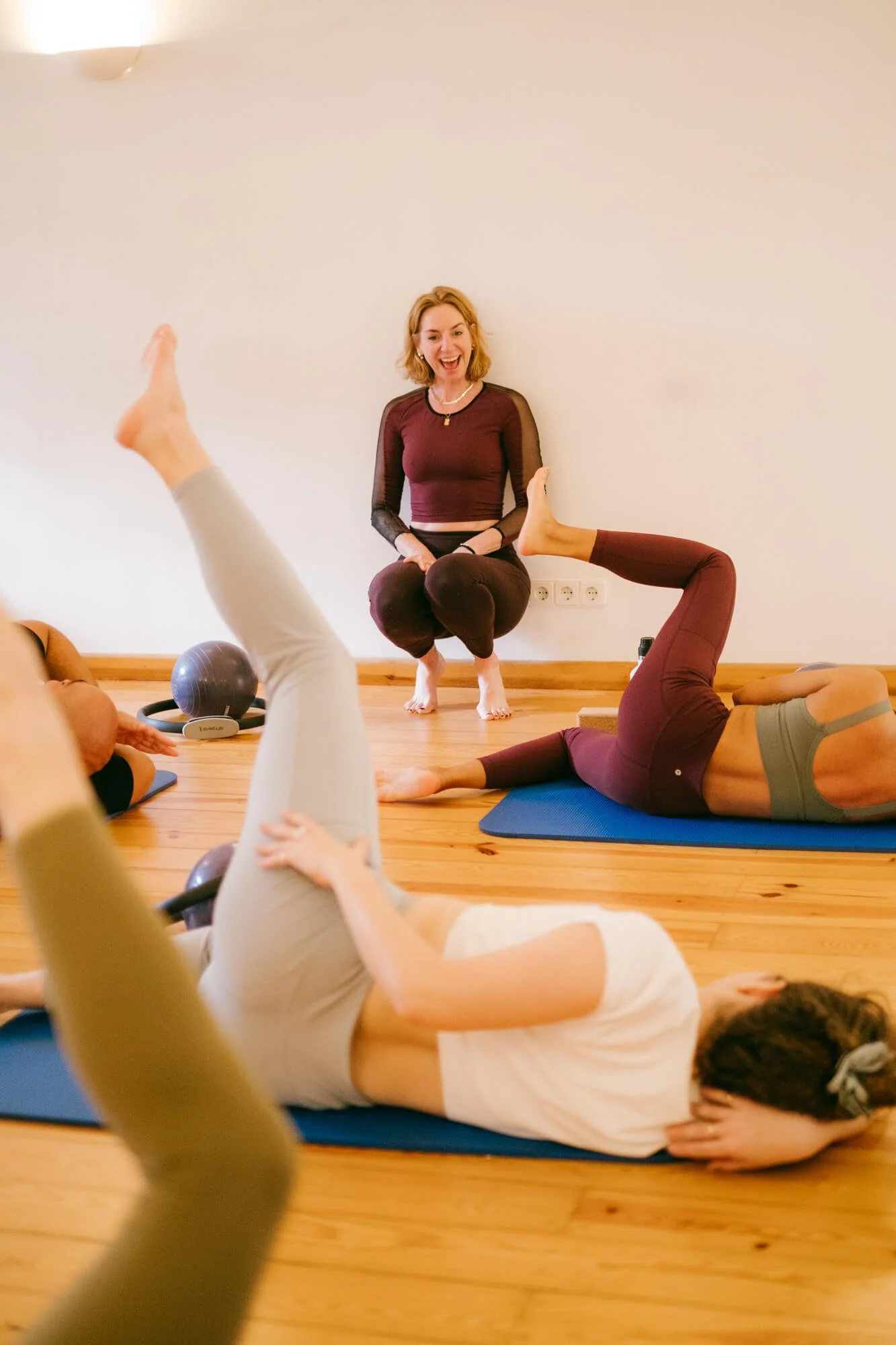 A group of people doing yoga on mats in a studio with a smiling instructor leading the class.