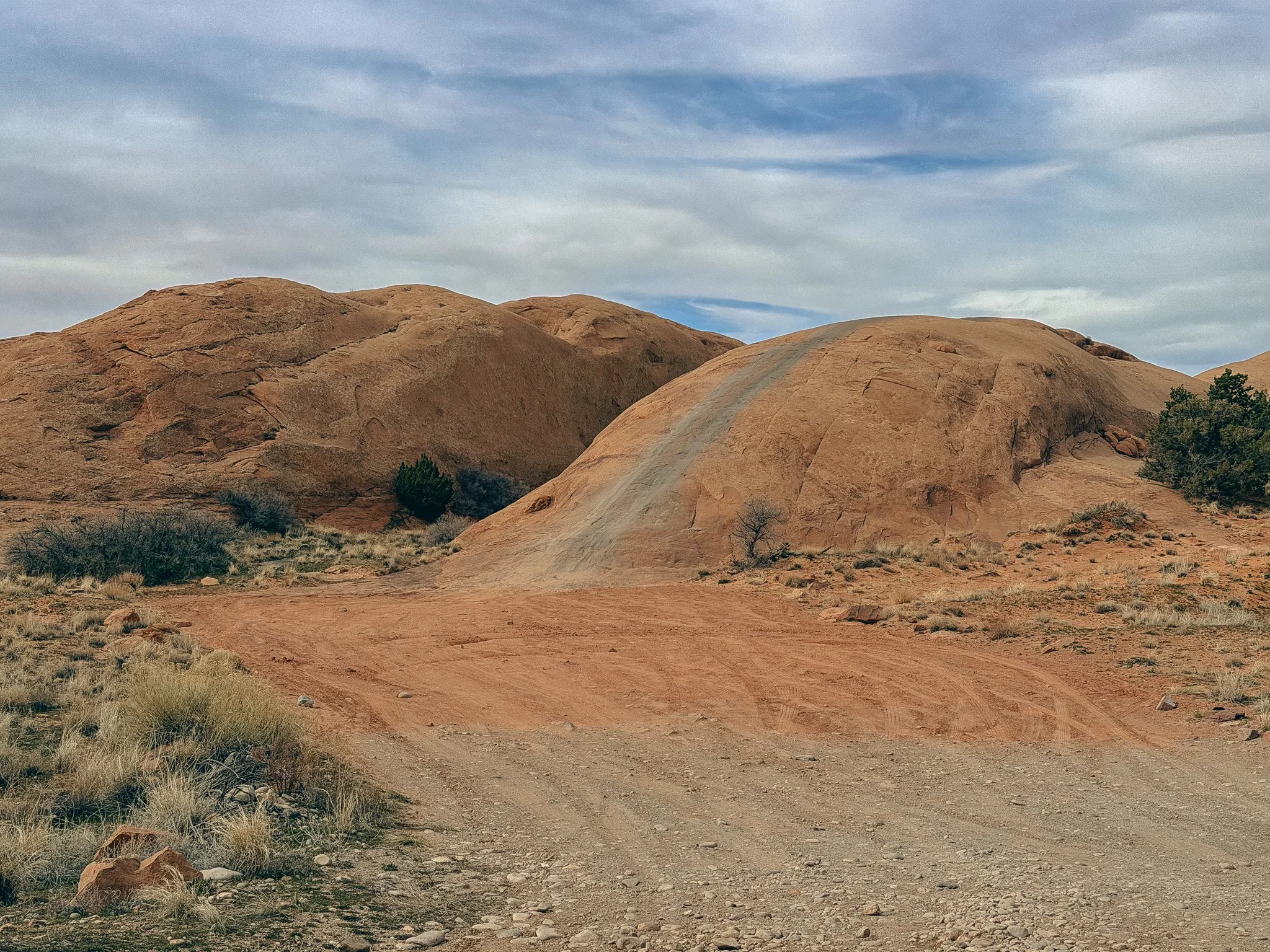 4x4 vehicle tracks climbing slickrock sandstone domes on Hell’s Revenge trail in Moab, Utah