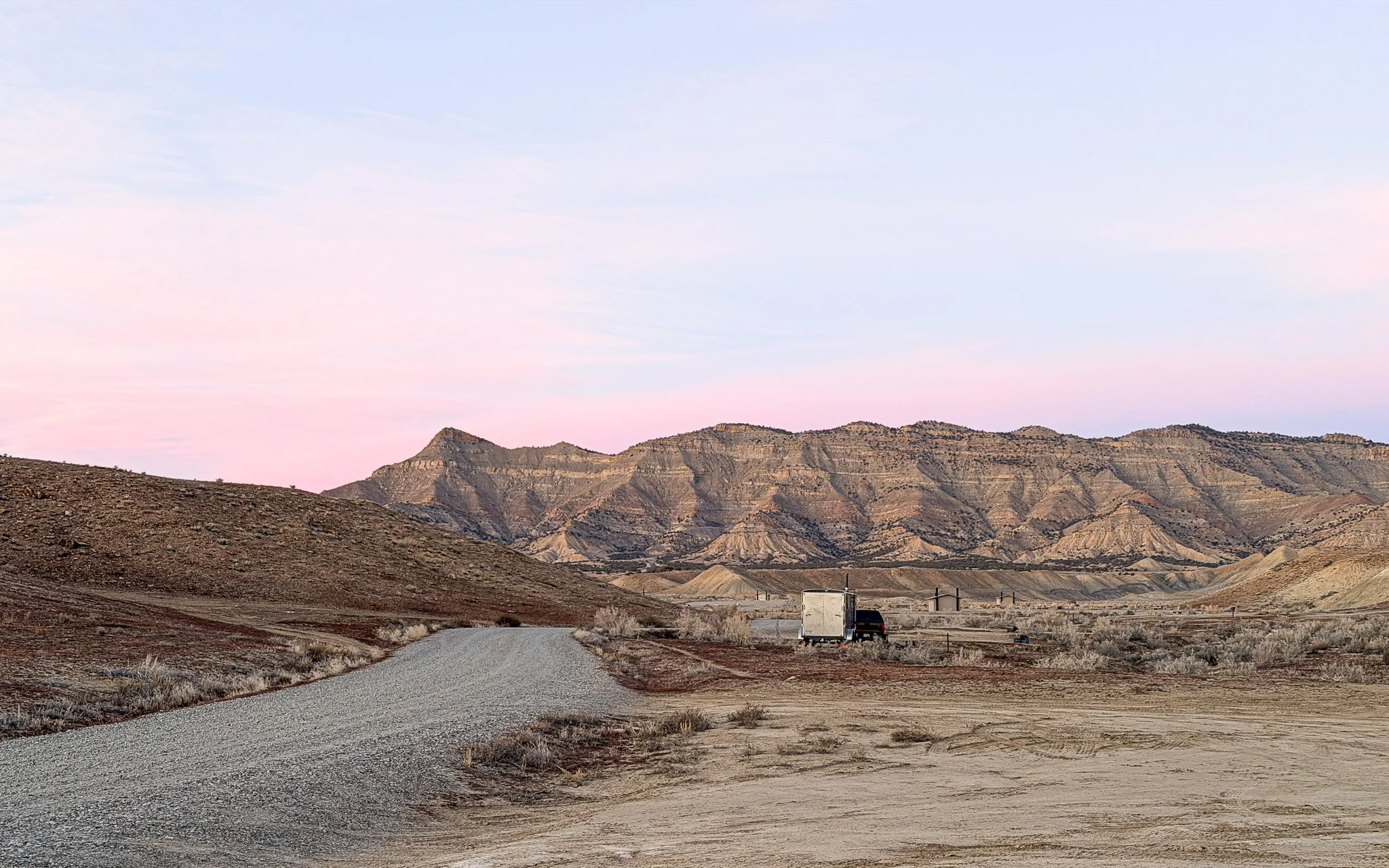 Gravel road leading to 18 Road mountain bike trails in Fruita Colorado with Book Cliffs at sunset