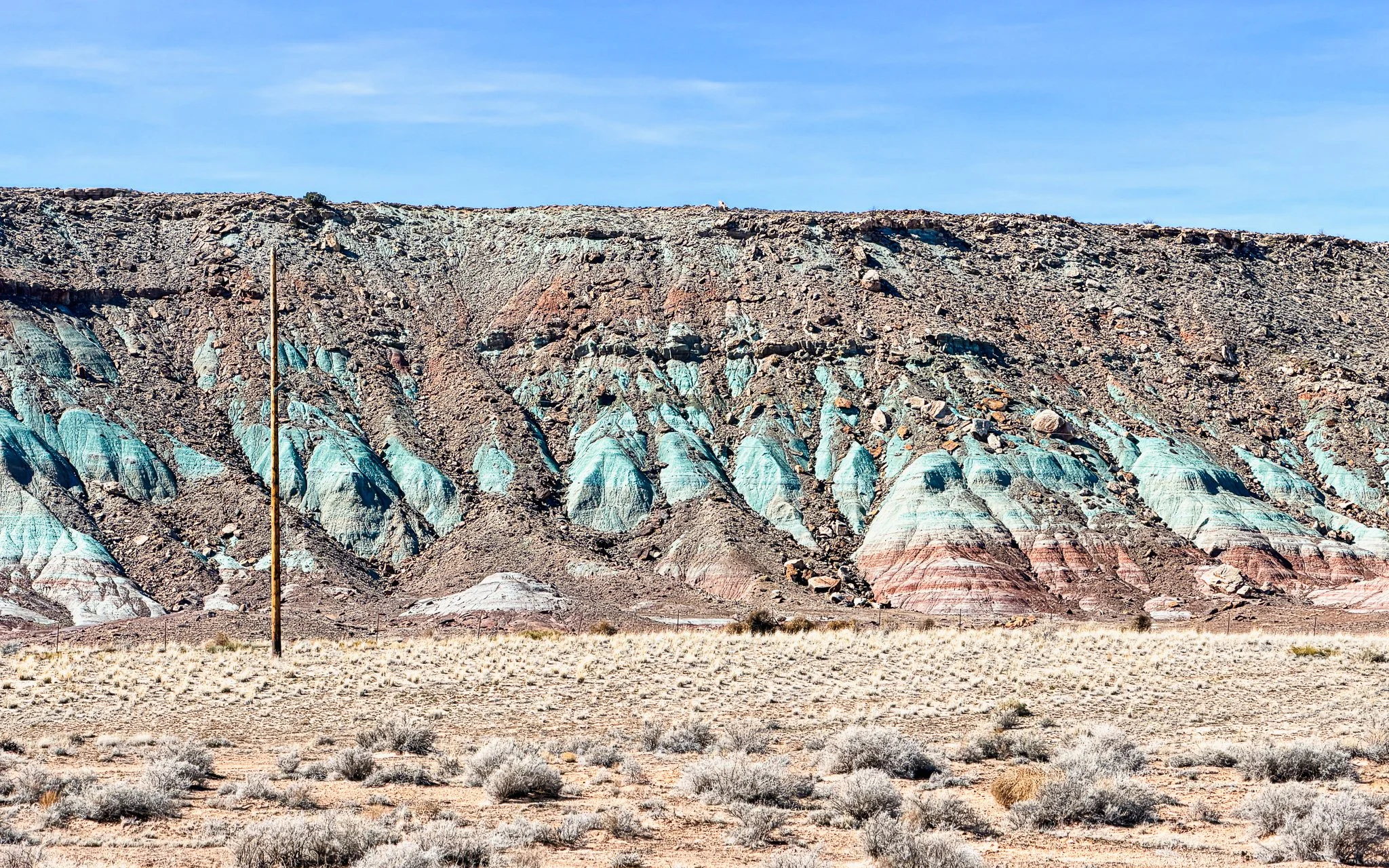 Multicolored rock layers near Utahraptor State Park outside Moab, Utah, showing green, red, and cream bands of the Morrison Formation formed in ancient floodplain environments.
