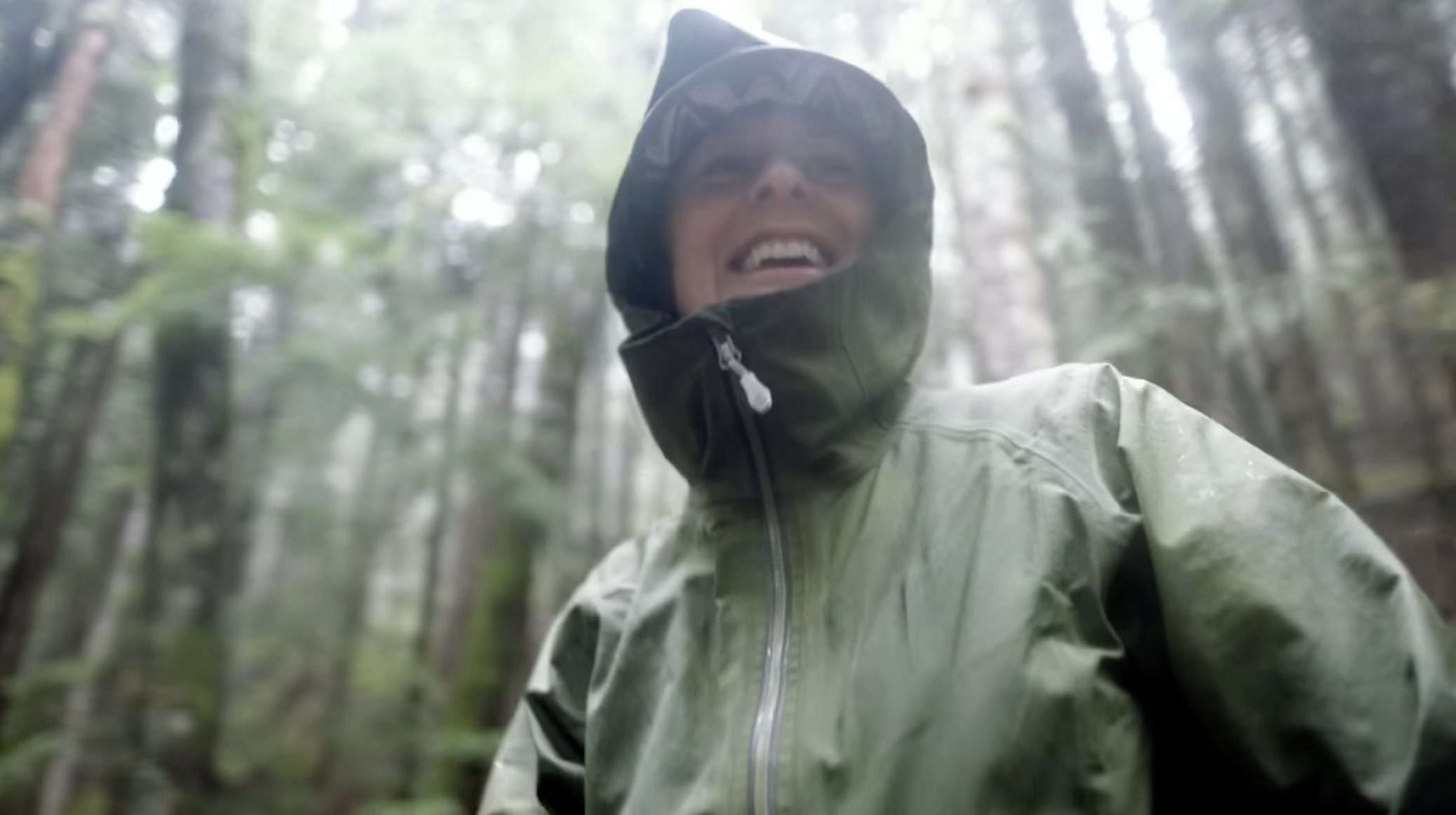 Woman wearing a green waterproof jacket in a forest during rain