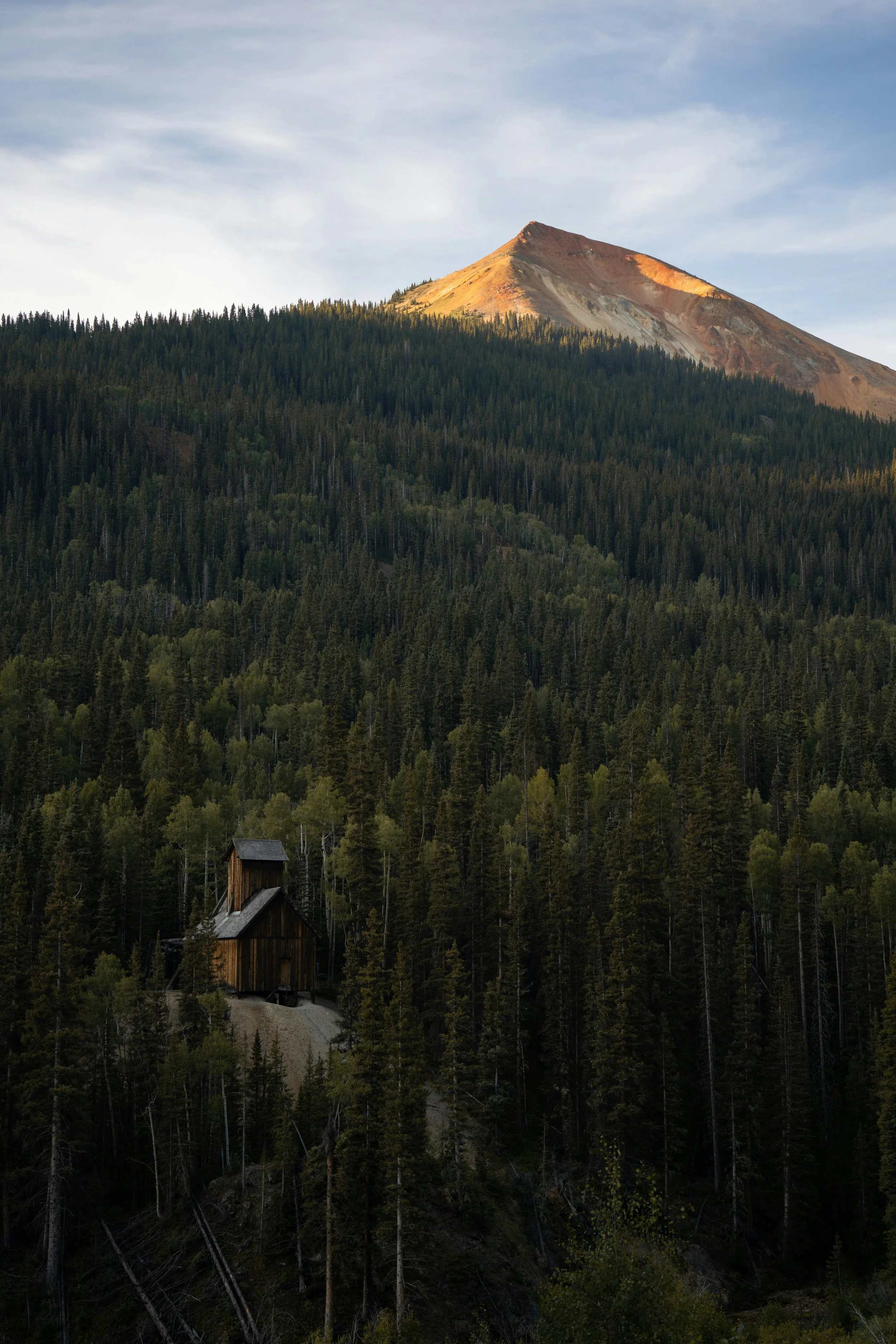 Historic mining structure surrounded by forest below Red Mountain in Colorado's San Juan Mountains.