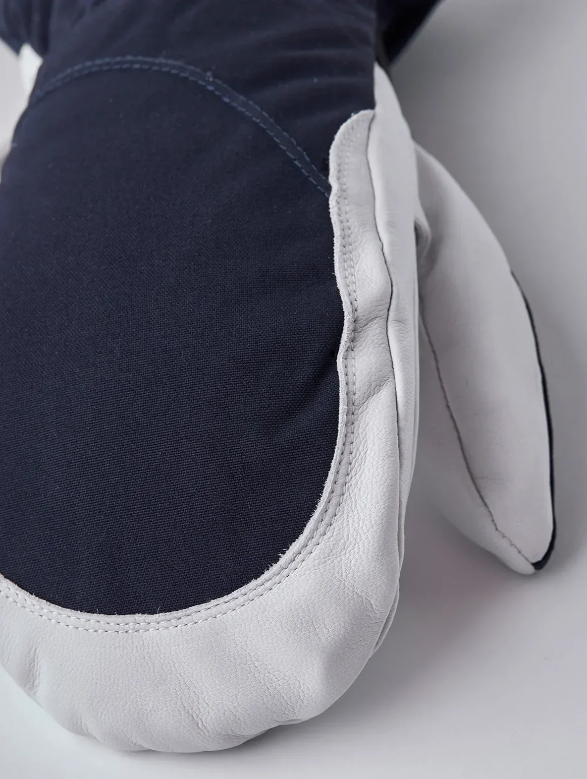 Close-up of the back of a Hestra Heli Ski Mitten showing dark fabric and white leather trim.
