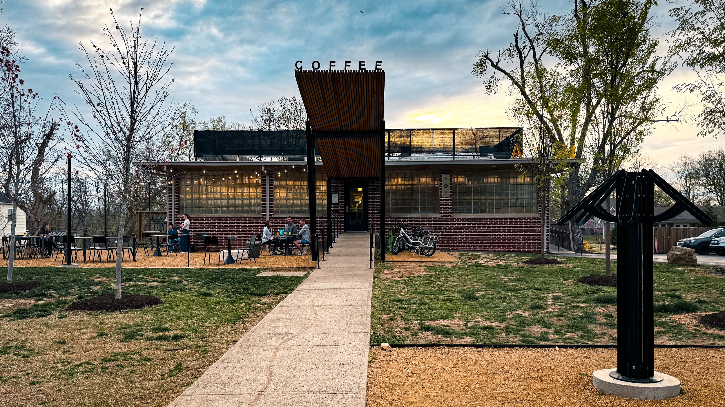 Exterior view of Airship Coffee’s Pumphouse location in Bentonville with outdoor seating and bicycles nearby.
