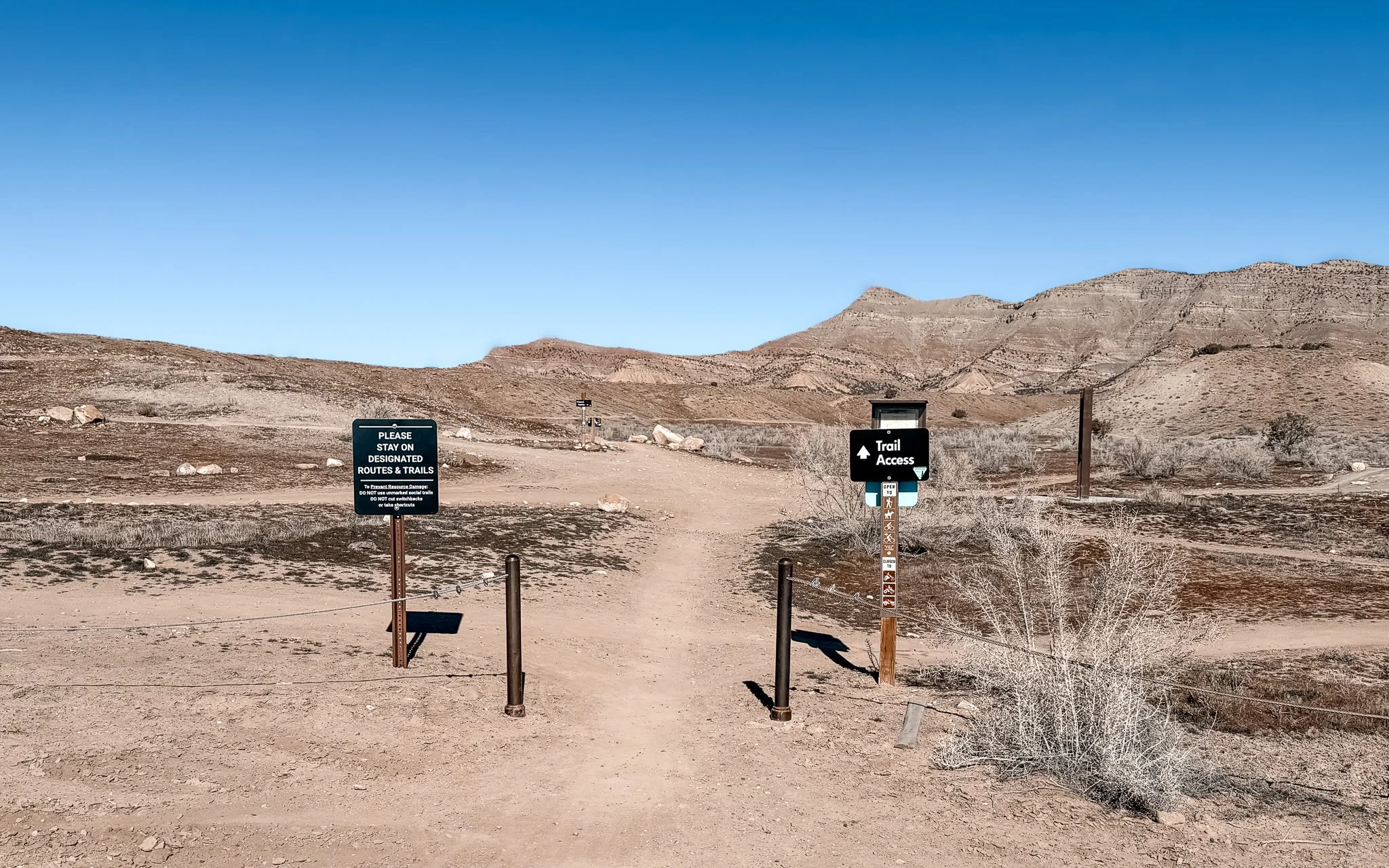 18 Road trail access sign on BLM land near Fruita, Colorado with desert hills and Book Cliffs in the background