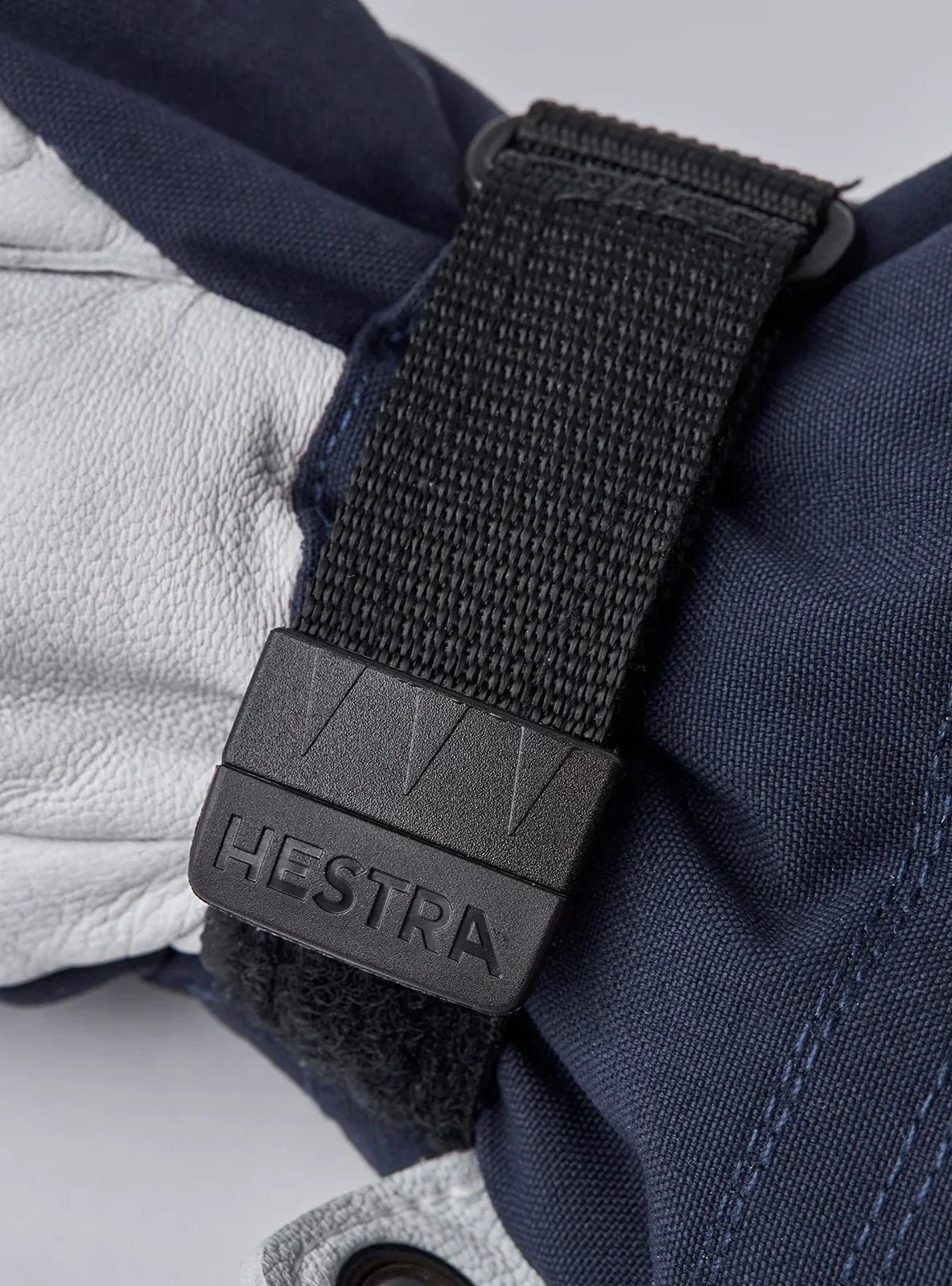 Close-up of the back of a Hestra Heli Ski Mitten showing dark fabric and white leather trim.