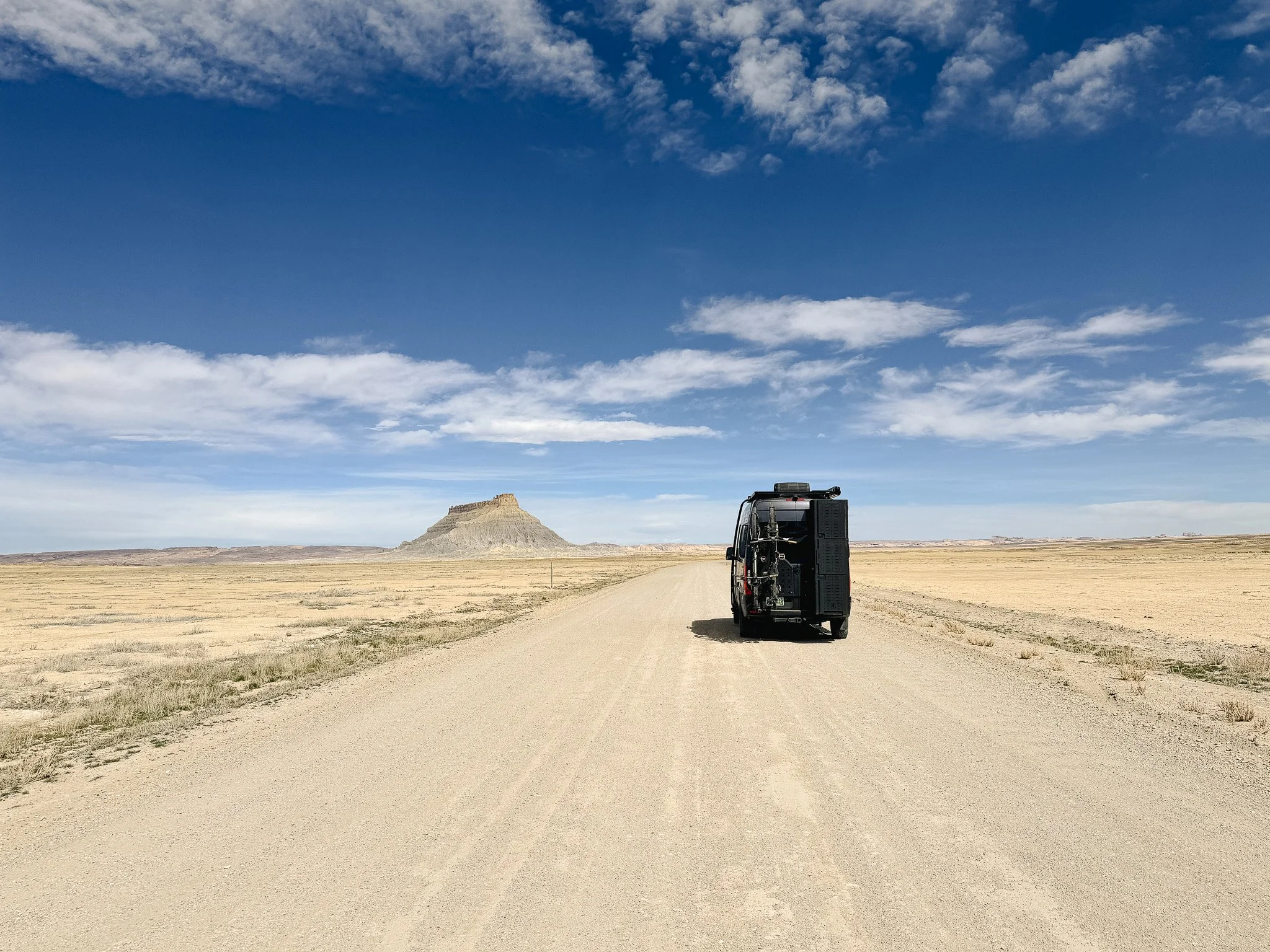 camper van driving on remote dirt road in Utah desert landscape