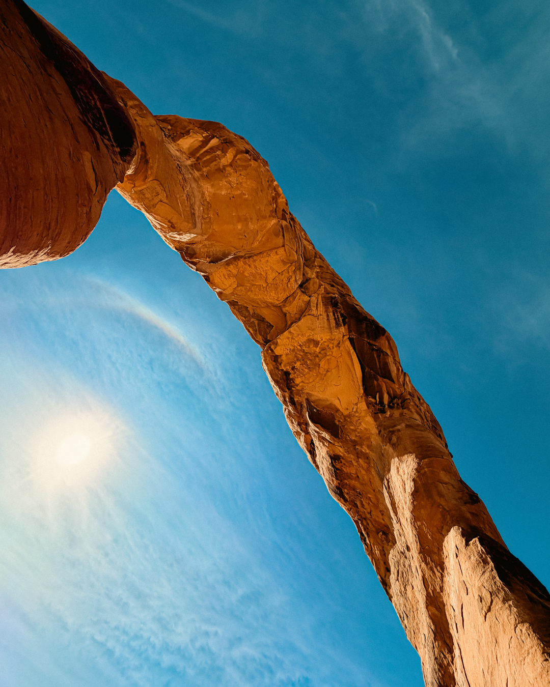 Upward view beneath Delicate Arch showing underside of sandstone arch and blue sky