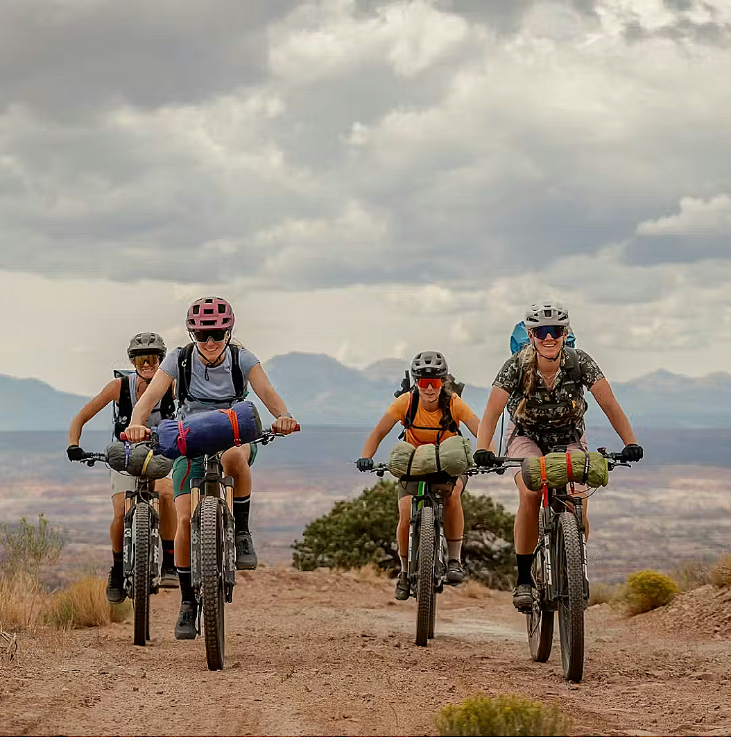 Group of women bikepacking on mountain bikes in desert landscape