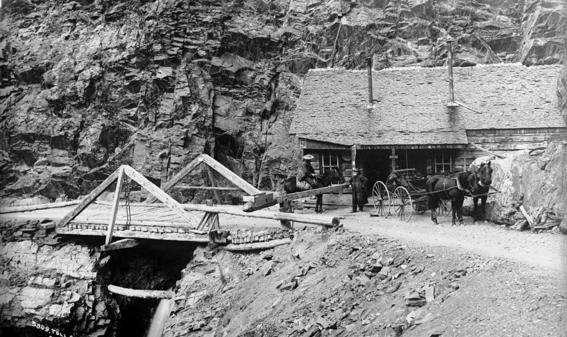 Historic photograph of the Otto Mears toll road with a bridge, horses and wagon in Colorado's San Juan Mountains.