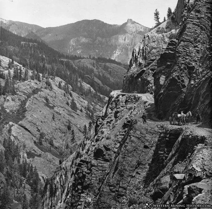 Historic mountain road cut into a cliff near Ouray, Colorado, with a horse-drawn wagon