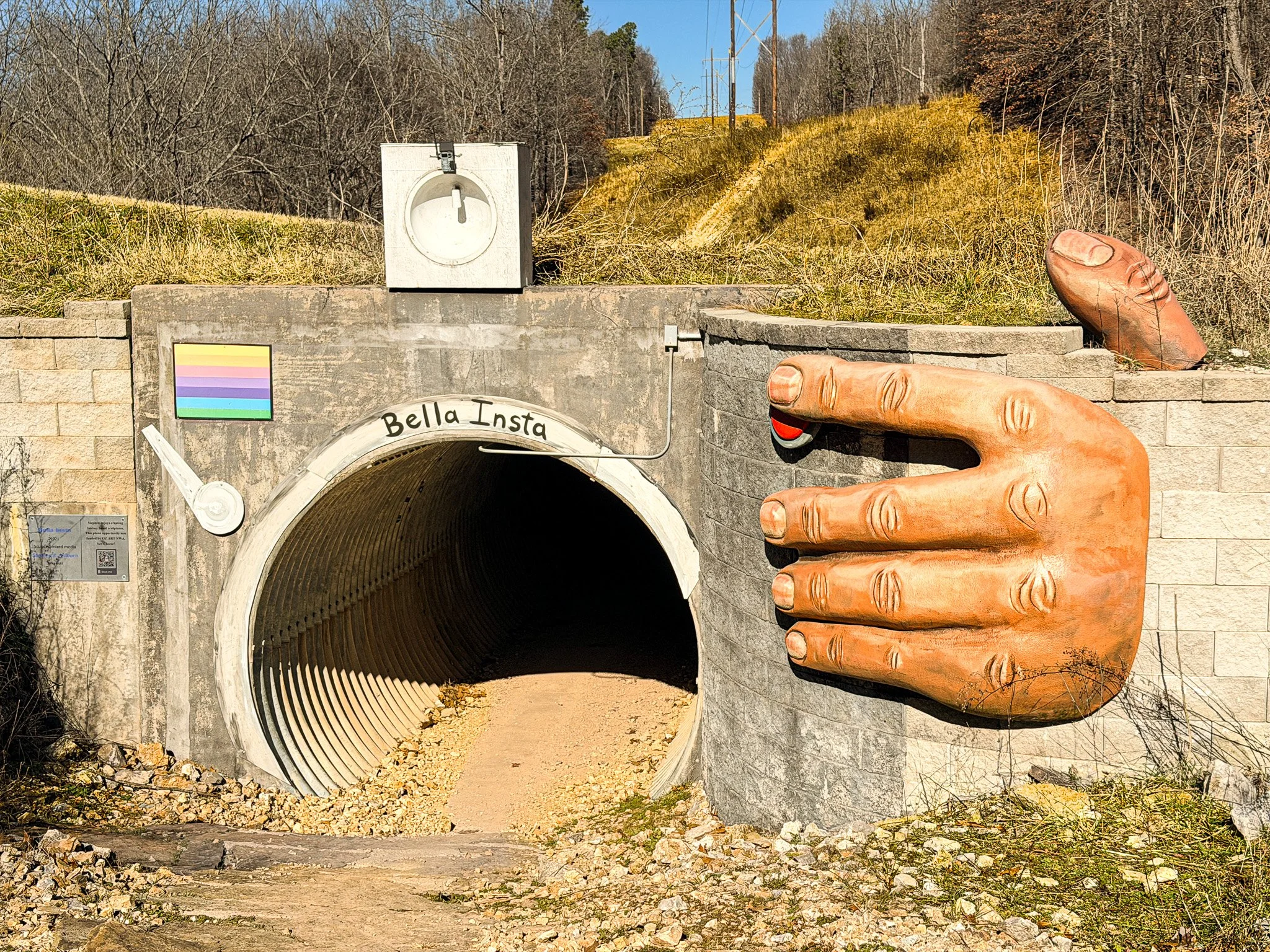 Concrete tunnel entrance with sculpted hand artwork along the Tunnel Vision mountain bike trail in Bella Vista, Arkansas.