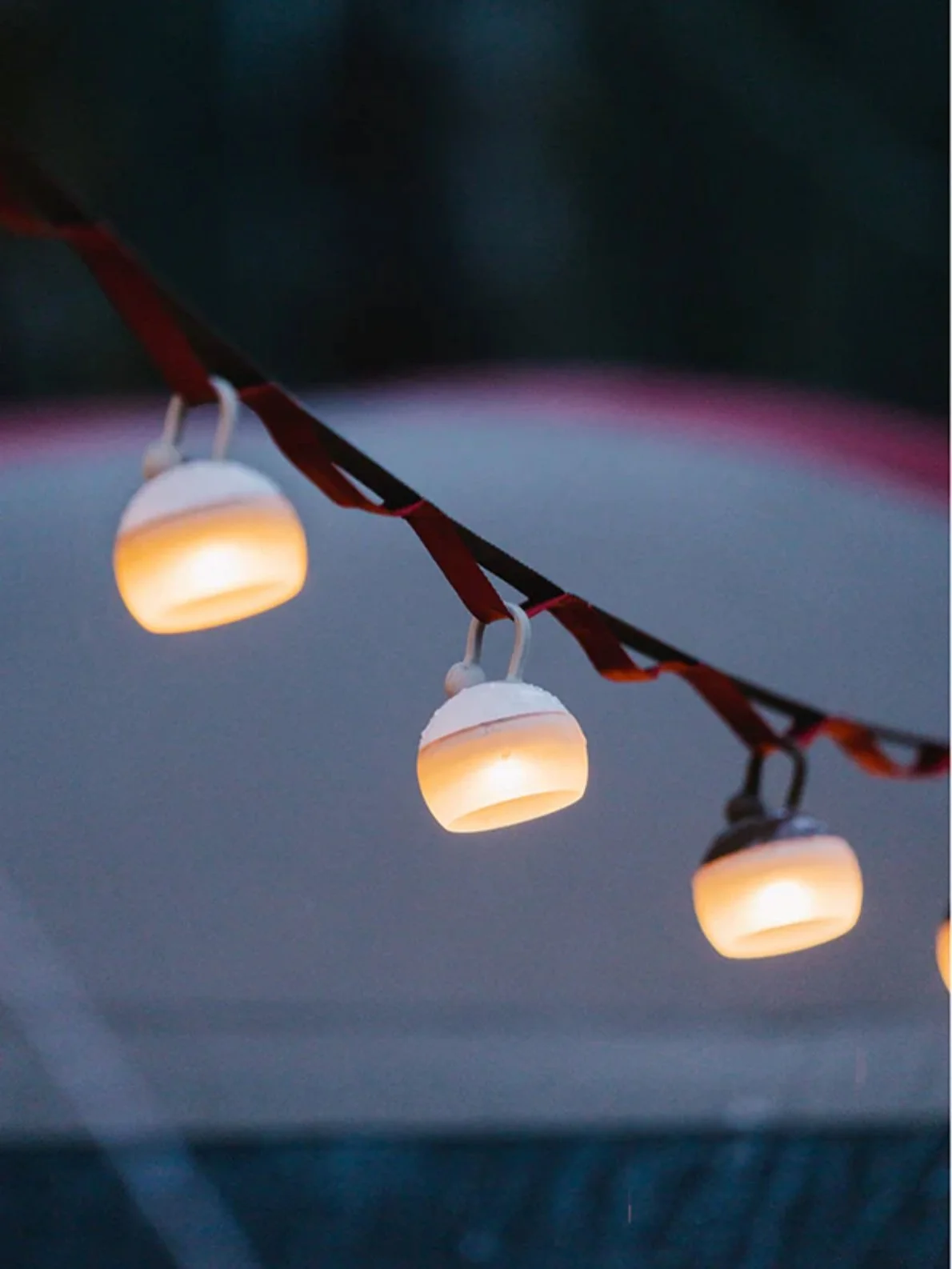 Close-up of Snow Peak Mini Hozuki lights strung on a daisy chain at dusk