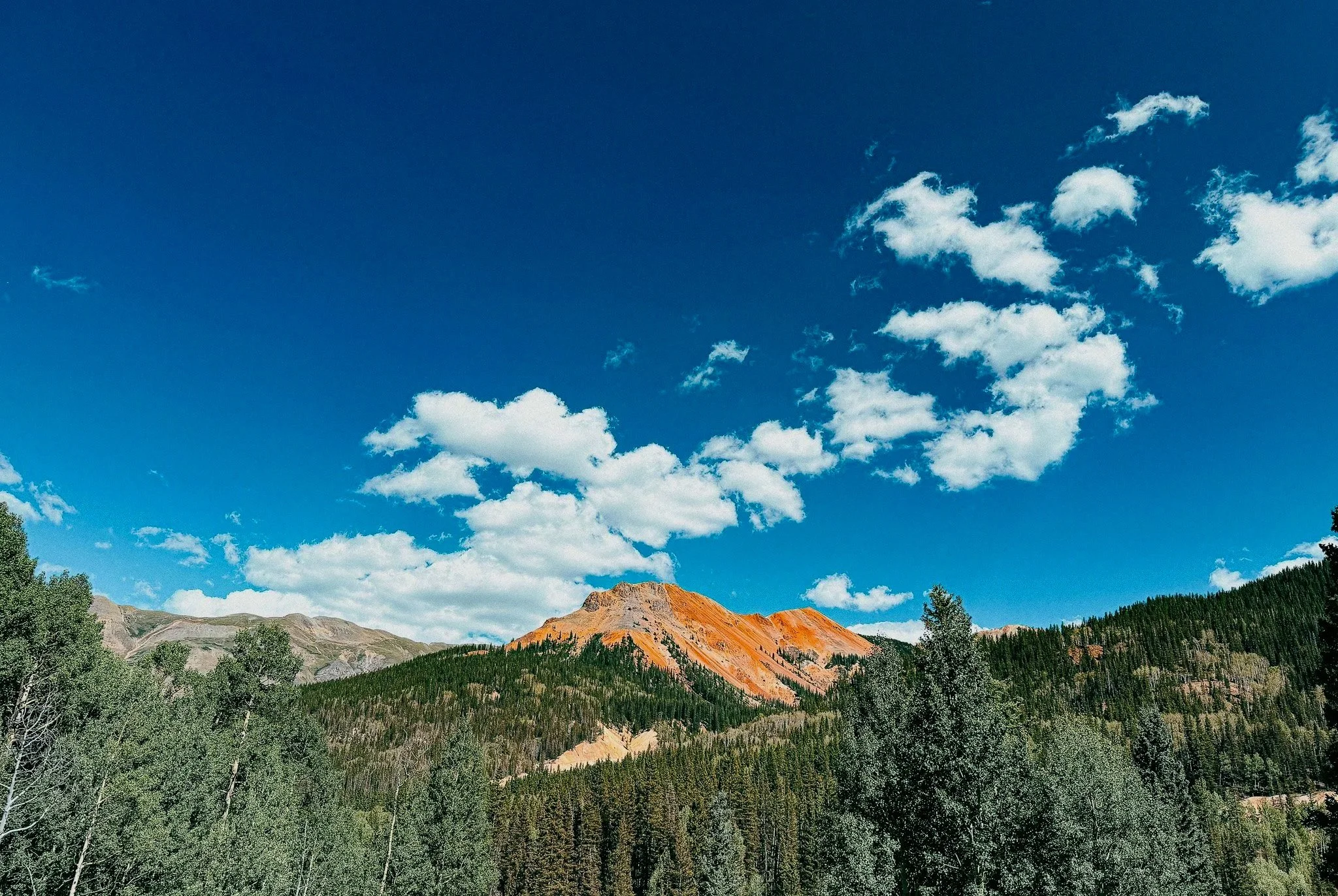 Red and orange mountain rising above the forest in Colorado's San Juan Mountains