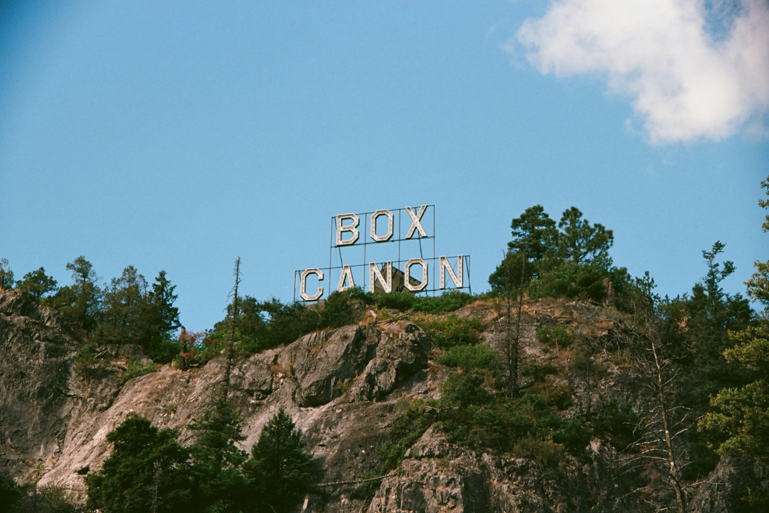 The "Box Canon" sign mounted on a rocky hillside above the entrance to Box Canyon Falls near Ouray, Colorado.