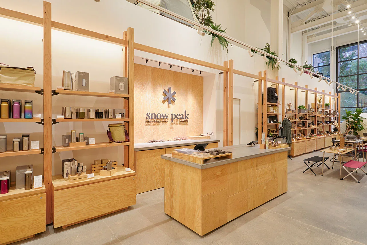 Snow Peak retail store interior with minimalist wood shelving and high-end camping gear displays