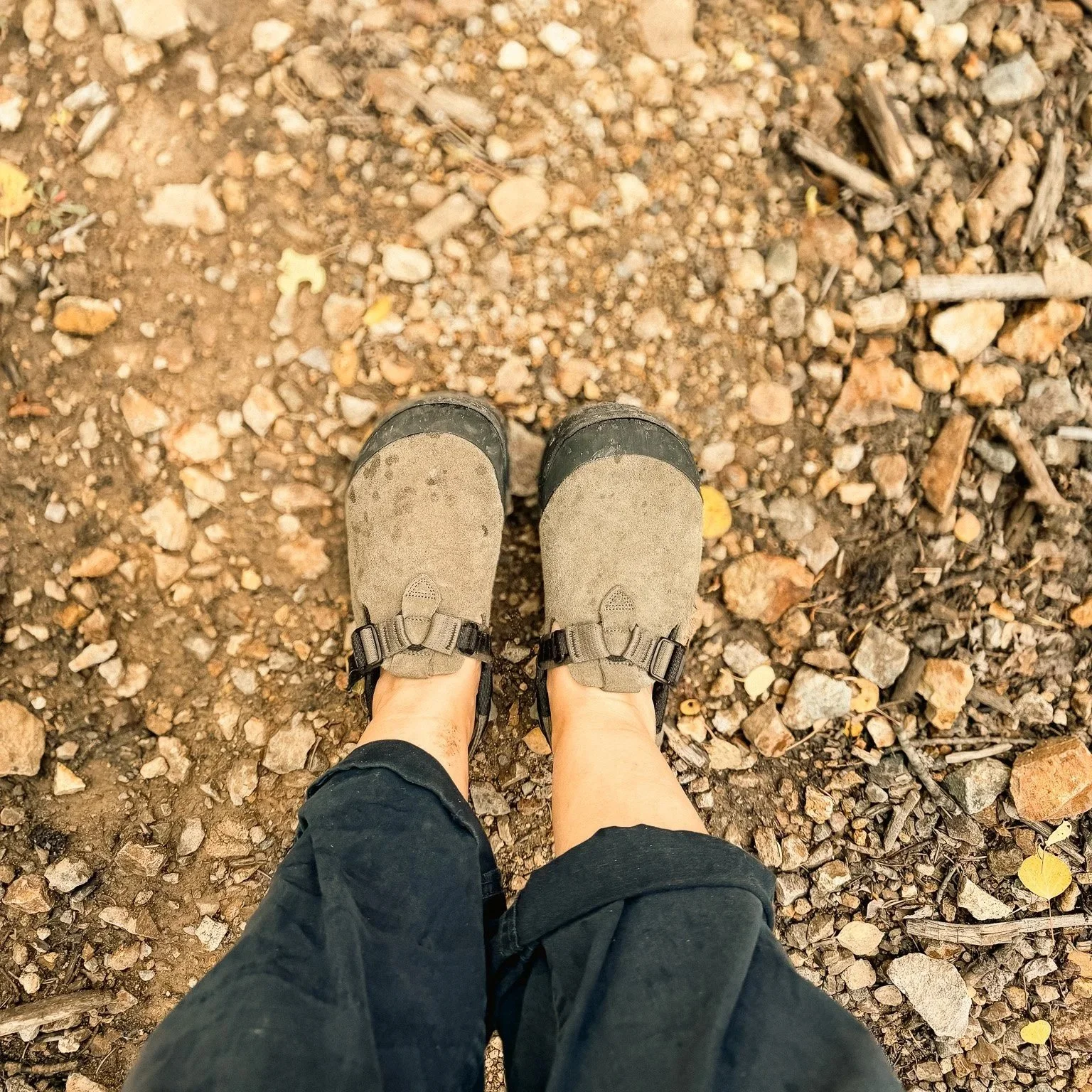 Looking down at my Sagebrush Bedrock Mountain Clogs while standing on a rocky dirt trail, showing the suede uppers and adjustable straps.