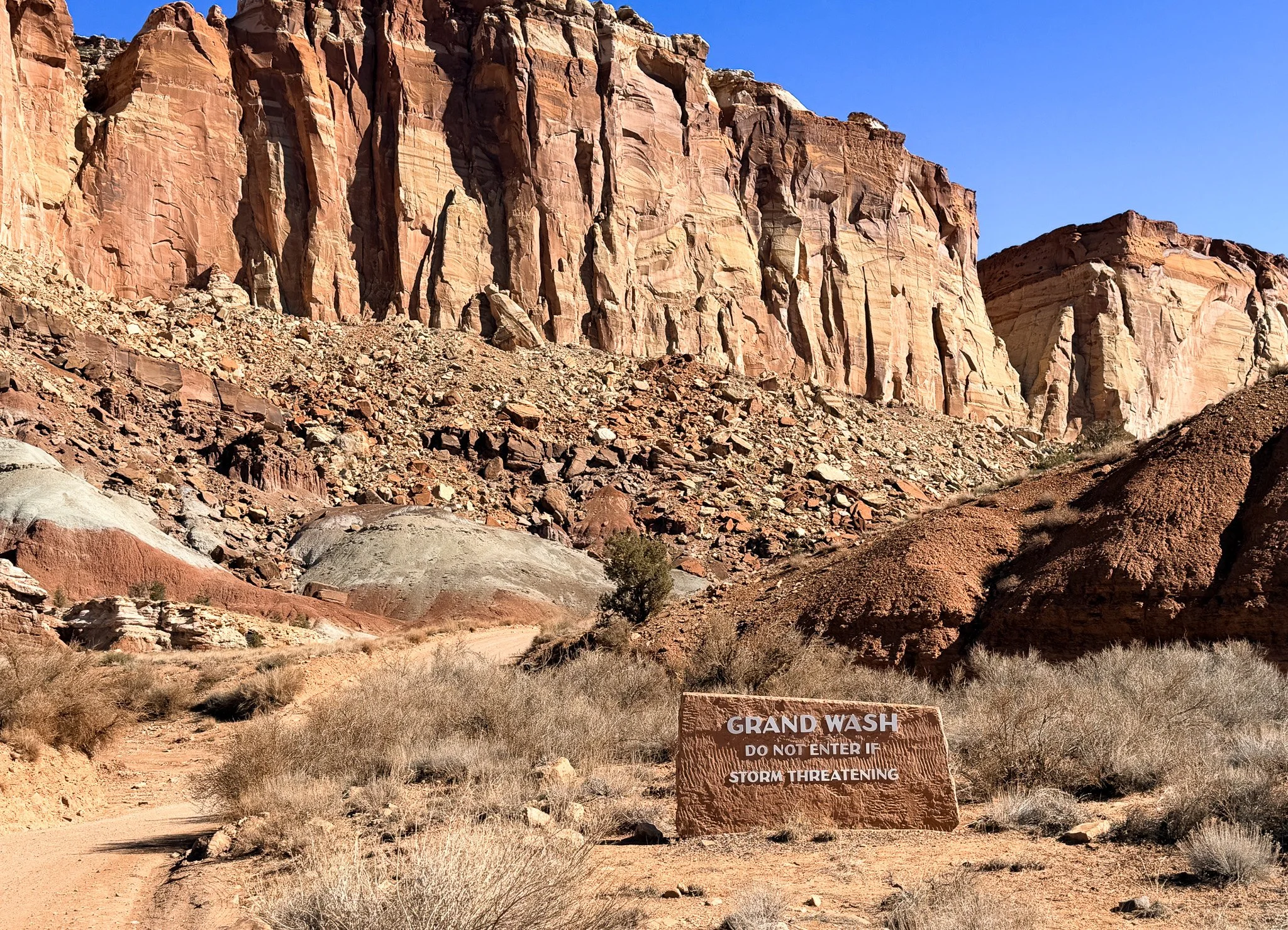 Grand Wash trail entrance sign beneath towering canyon walls in Capitol Reef National Park Utah