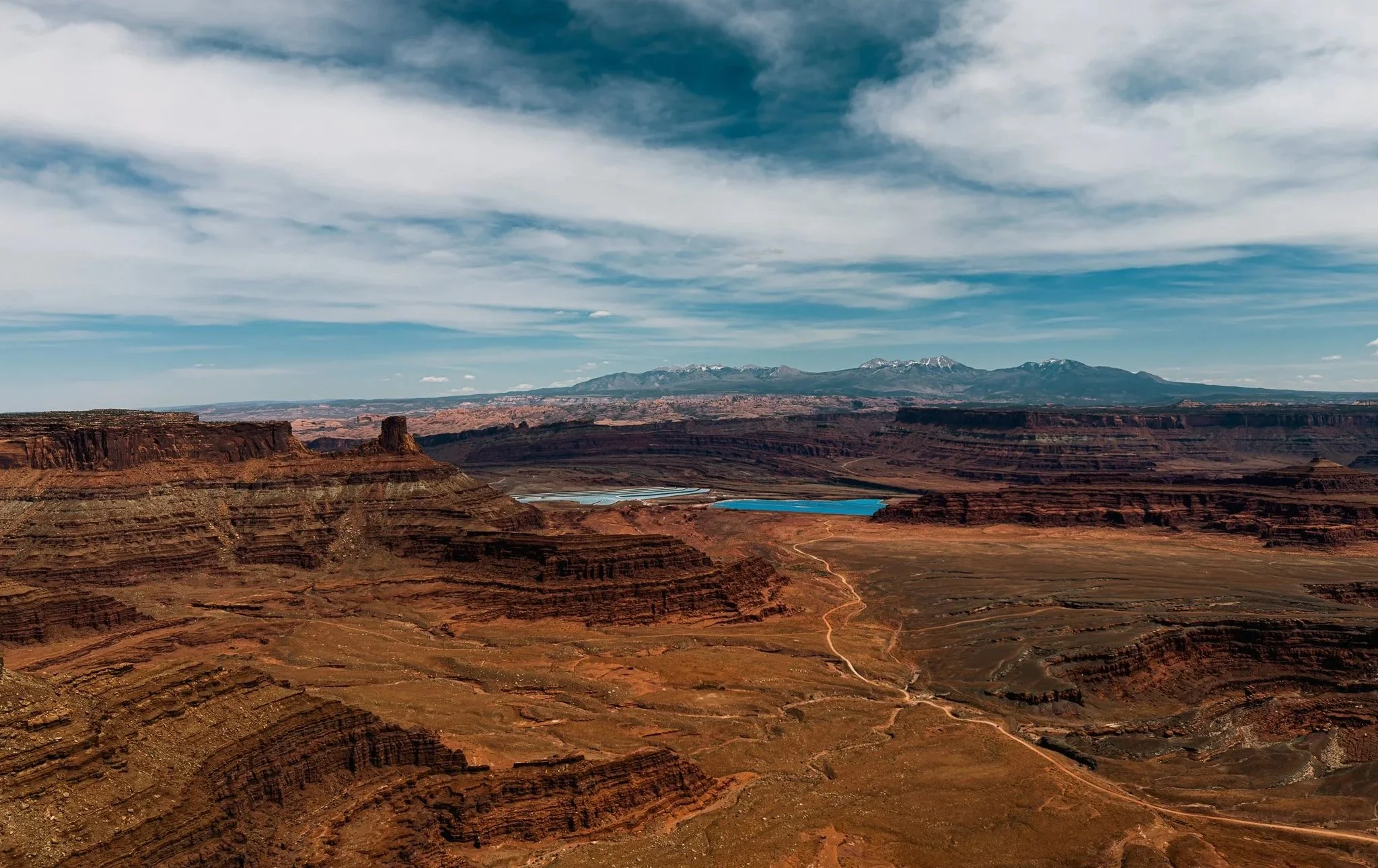View from Dead Horse Point State Park showing Shafer Trail leading toward the Potash ponds with the La Sal Mountains in the distance.