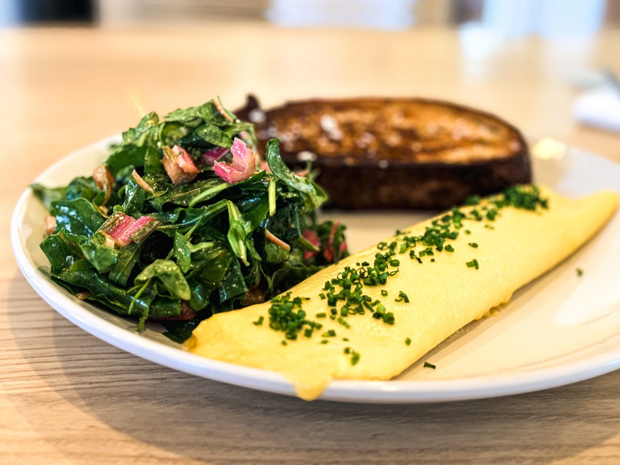 French omelet with chopped chives, sautéed greens, and bread dipped in butter with sea salt at Cafe Fritz in Hygiene, Colorado.