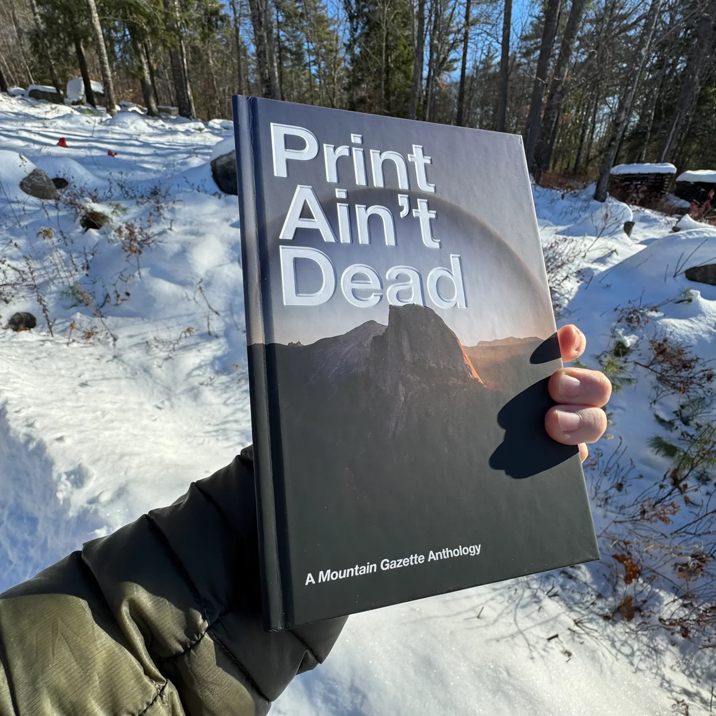 Print Ain’t Dead Mountain Gazette anthology book held outdoors in snowy landscape