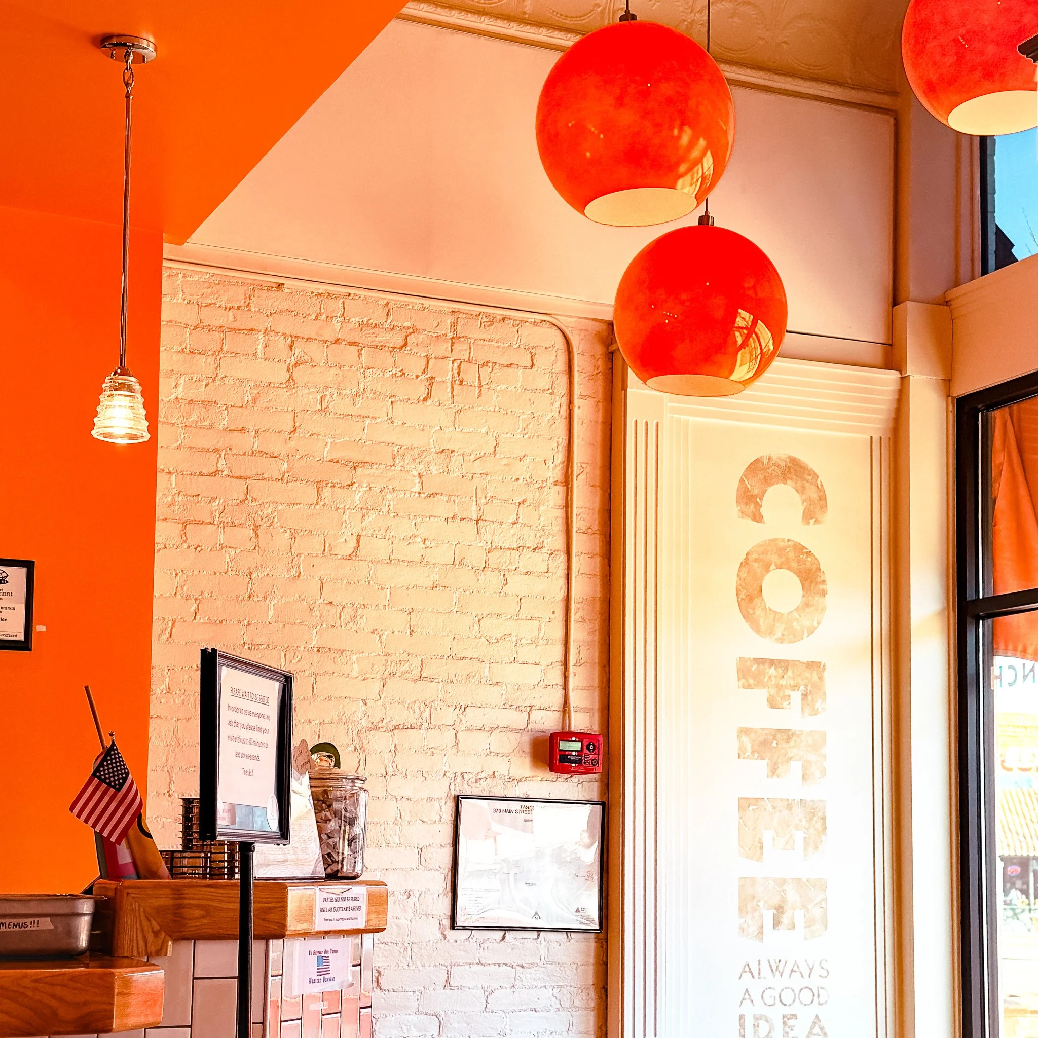 Interior of Tangerine restaurant in downtown Longmont, Colorado with orange pendant lights and exposed brick walls.